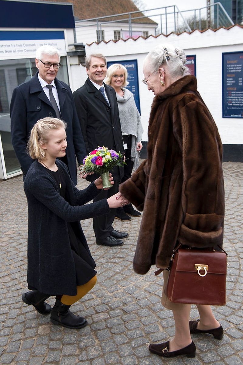 Dronningen hilser på blomsterpigen 11-årige Ester Wowk Vestergaard, museumsdirektør Thomas Bloch Ravn, bestyrelsesformand Peter Kjær og Pernille Bruun, da hun ankommer til åbningen af udstillingen Fra Dronningens Garderobe i Den Gamle By i Aarhus. (Foto: Bo Amstrup/Scanpix 2018)