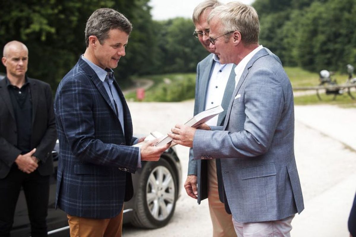 Kronprins Frederik (tv) modtog en gave i form af en bog og et stykke kridt fra direktør i Geocenter Møn, Nils Natorp (th) og Peter Scavenius, formand i Geocenter Møn. Foto: Ida Marie Odgaard/Scanpix