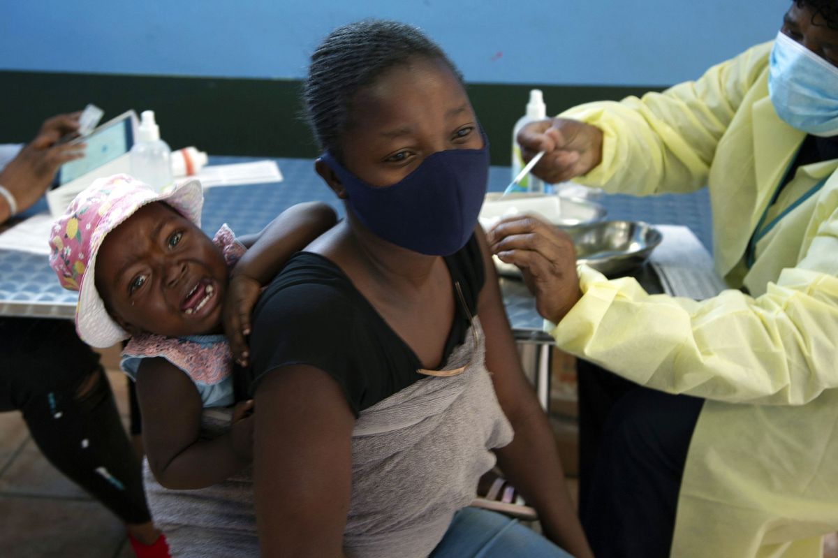 En kvinde med et grædende barn på ryggen får en coronavaccine i Diepsloot Township tæt ved Johannesburg torsdag. Sydafrika har opdaget en ny variant, der vækker bekymring hos forskerne.