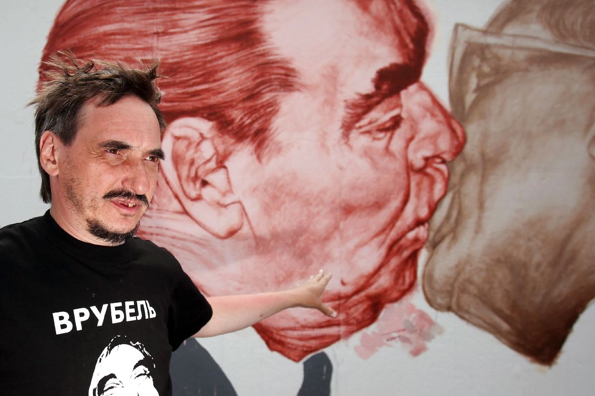 Den russiske kunster Dmitri Vrubel, der her ses ved sit berømte værk på Berlinmuren i 2009, er død. Han blev 62 år.
