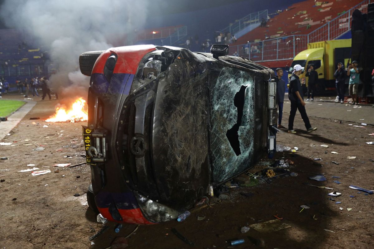 En udbrændt bil efterladt på gaden efter optøjer ved fodboldkamp i Indonesien. Mindst 129 meldes døde.