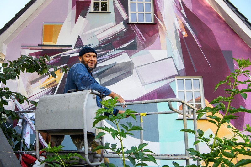 Linjer og geometriske former er Augustine Kofies ting. Før han går i gang med farverne, bruger han en kridtsnor til at strege hele gavlen op med. Foto: Henrik Bo