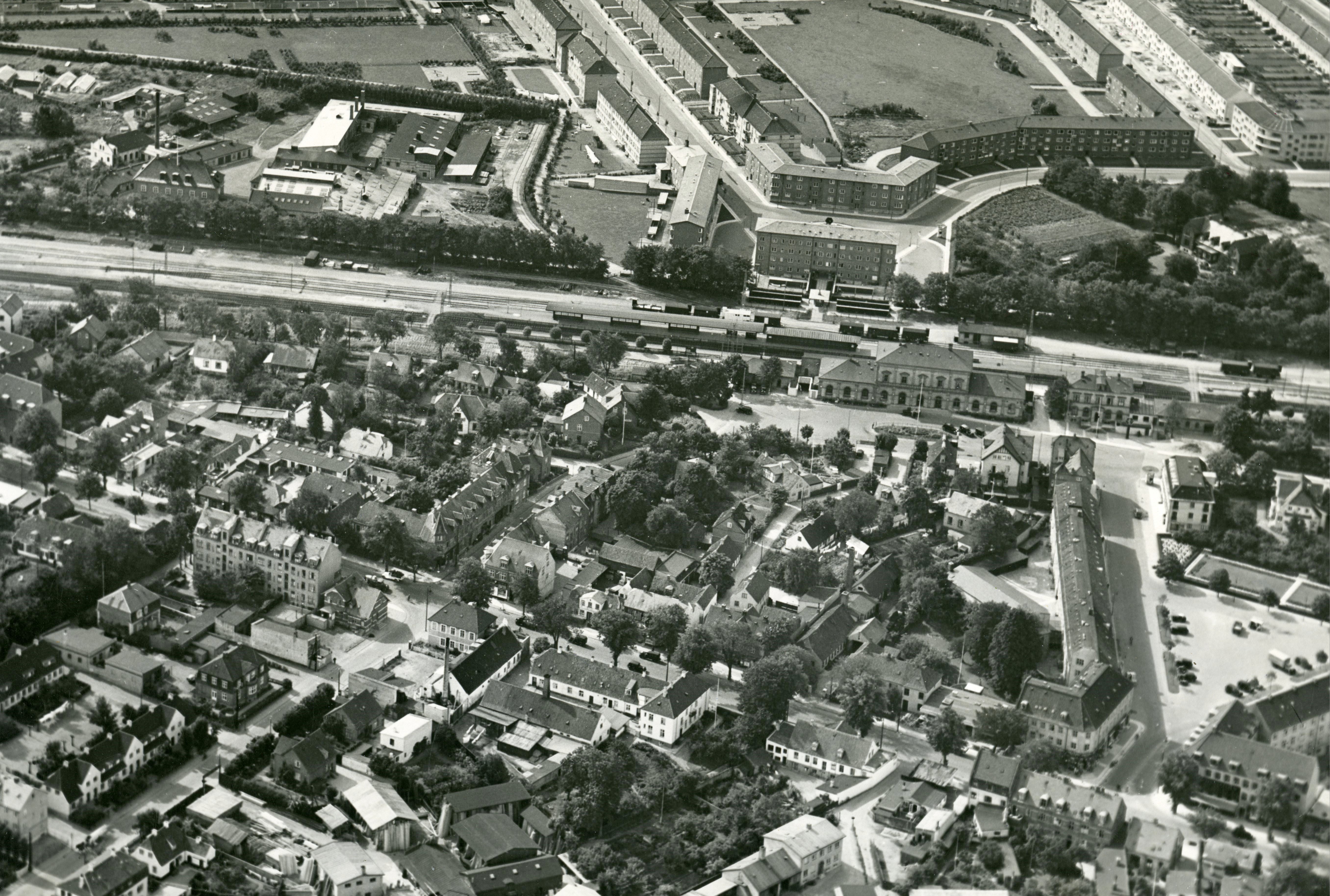 Luftfoto af Lyngby bymidte set mod sydvest, 1938. Øverst ses Ulrikkenborg Plads og Lyngby Station, og nederst Lyngby Hovedgade. Bemærk at rådhuset endnu ikke er opført. Det blev indviet i 1941. Foto: Lyngby-Taarbæk Stadsarkiv