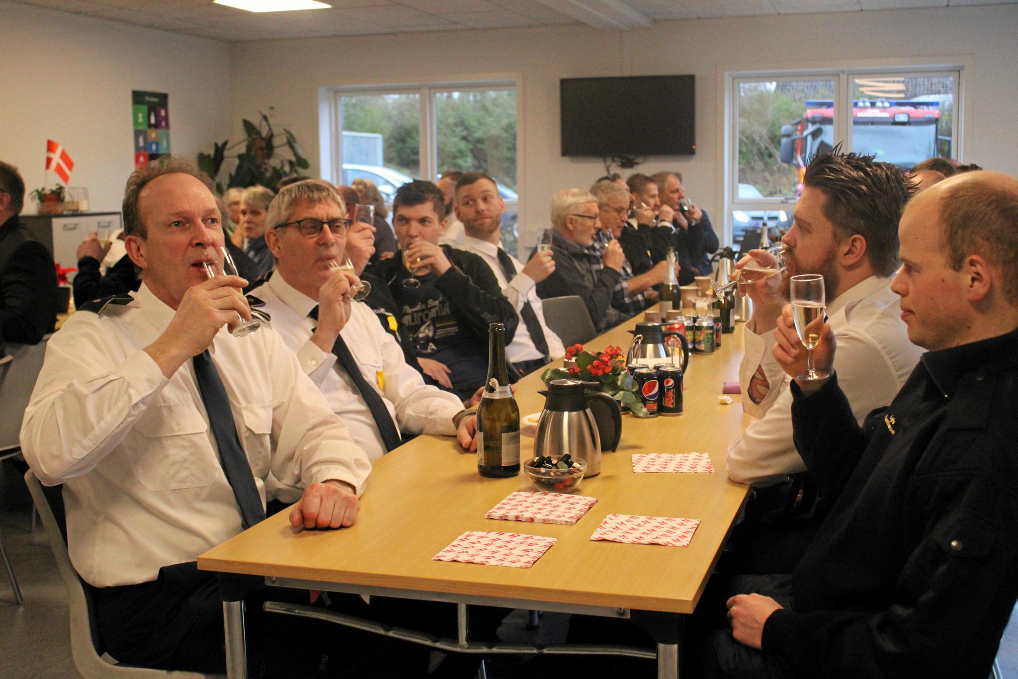 Et enkelt glas champagne blev det til under nytårsparolen for Lejre Brandvæsen. Og Ove Svendsen, der ses til venstre, fortjener det virkelig - han fik overrakt hæderstegn efter 25 års tro tjeneste i brandvæsenet. Foto: Agnete Vistar