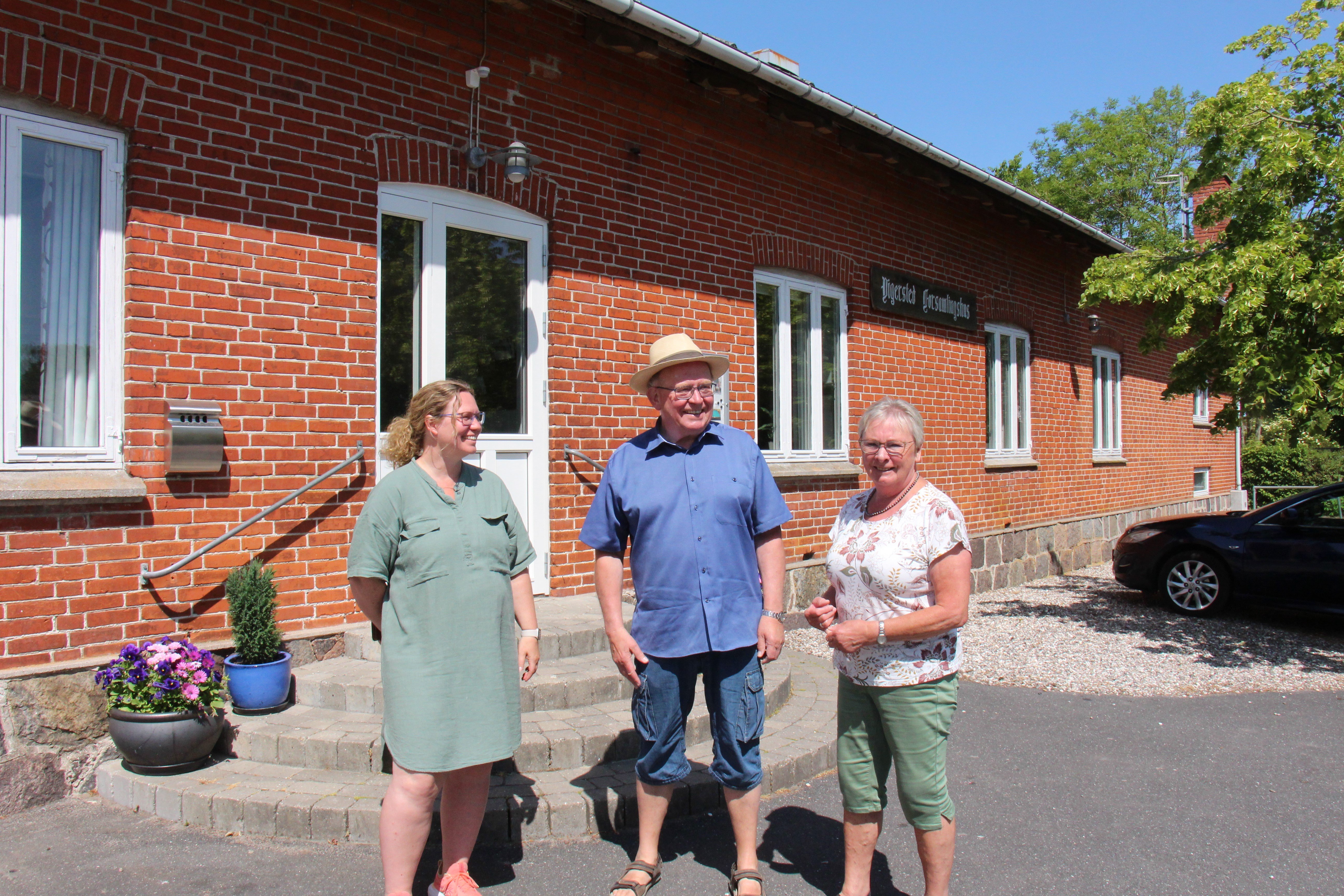 Christina Bonita, Torben Dan Jensen og Mathea Jensen foran De 100 hændelsers hus - Vigersted Forsamlingshus.