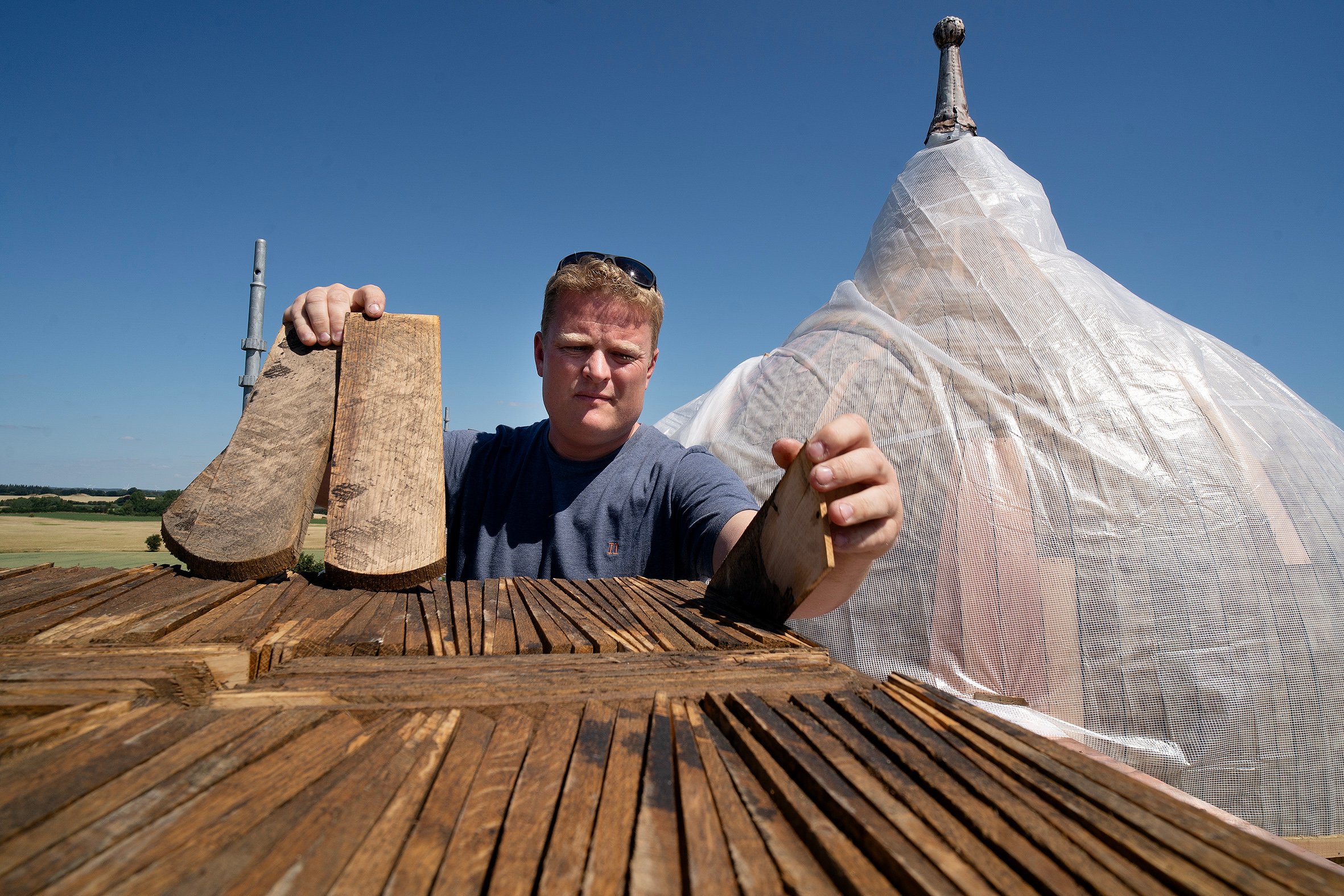 Møllebygger Christoffer Palle på toppen af den gamle mølle i Karrebæk. Møllehatten skal forsynes med 18.000 nye spån, som skal bankes i med en hammer. Foto: Thomas Olsen