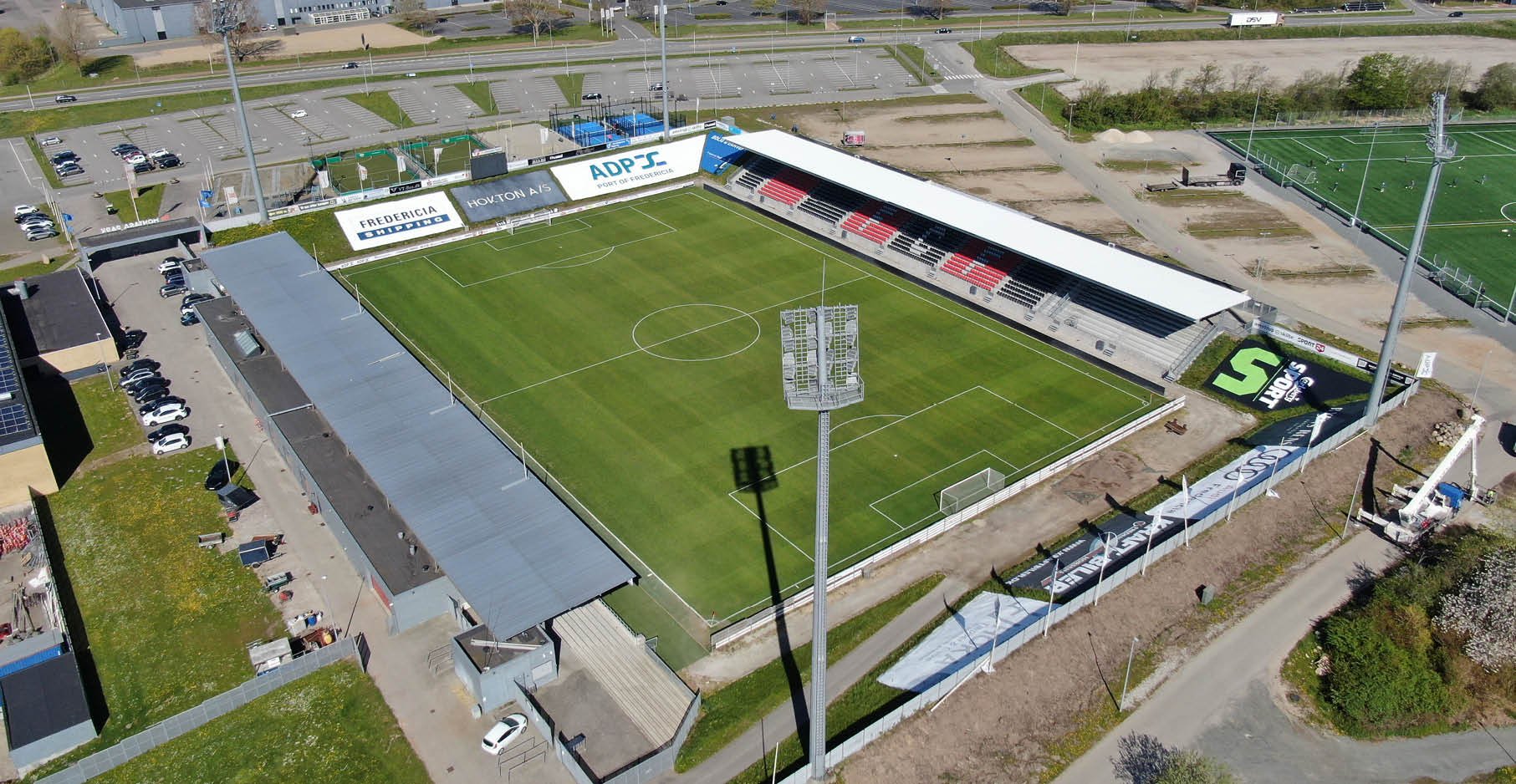 Næstved Boldklub sigter efter en ny sidetribune, der minder om den FC Fredericia fik bygget i 2021 på Monjasa Park (t.h.). Foto: FC Fredericia