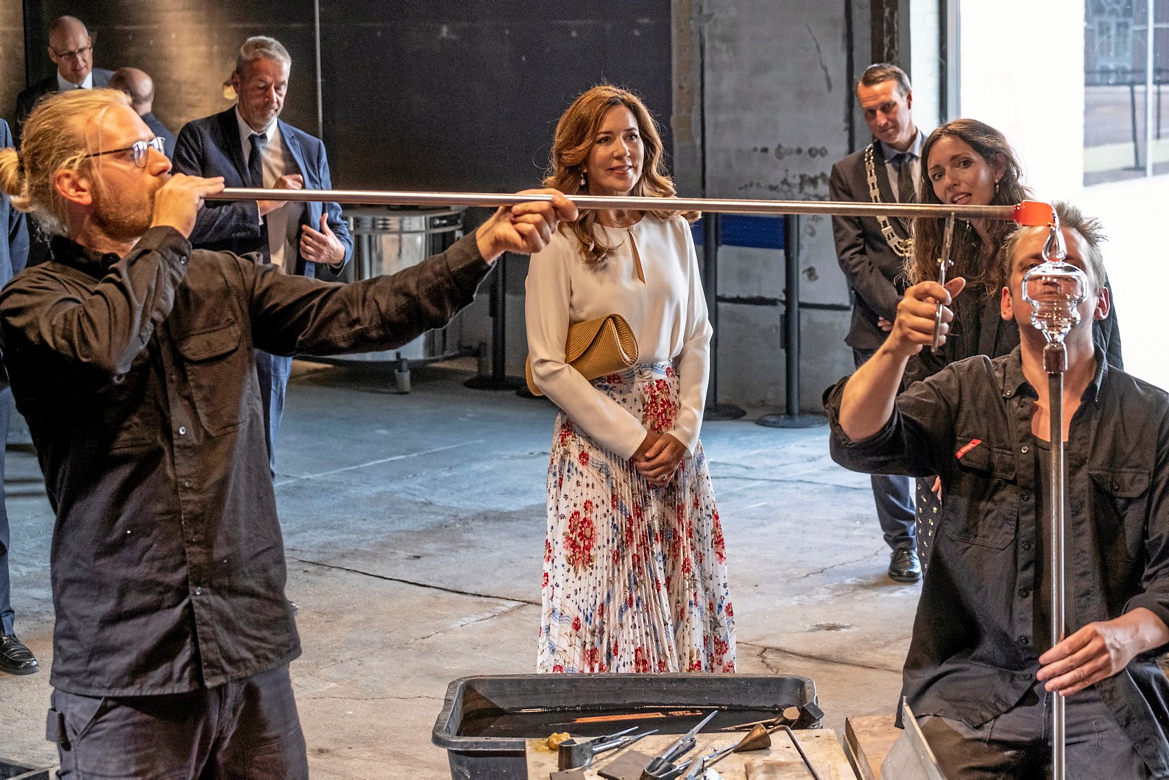 Glaspusterne Jonas Niedermann (t.v.) og Bjørn Friborg i gang i glasværkstedet ved den officielle åbning af Holmegaard Værk i juni 2020, hvor glasdesigneren Nina Nørgaard fortæller daværende kronprinsesse Mary om tilblivelsen af det champagneglas, som de er i færd med at lave.