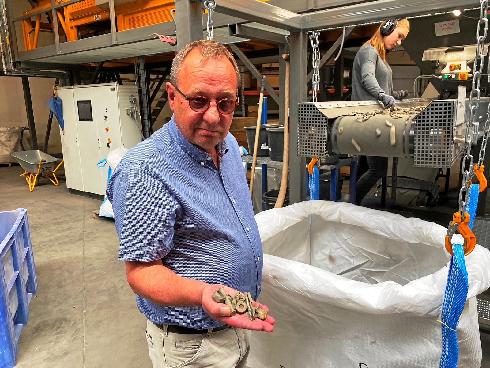 Direktør Ejvind Pedersen fremviser her noget af den messing, som udvindes af slaggerne, efter at de har været en tur gennem maskinerne i baggrunden.