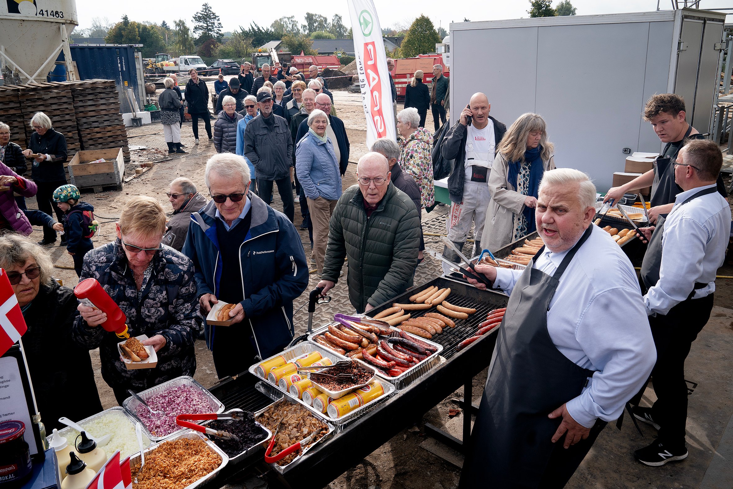 Købmand Michael Møller havde indkøbt masser af pølser. Han stod glad og uddelte dem til de mange gæster, som kiggede forbi rejsegildet.