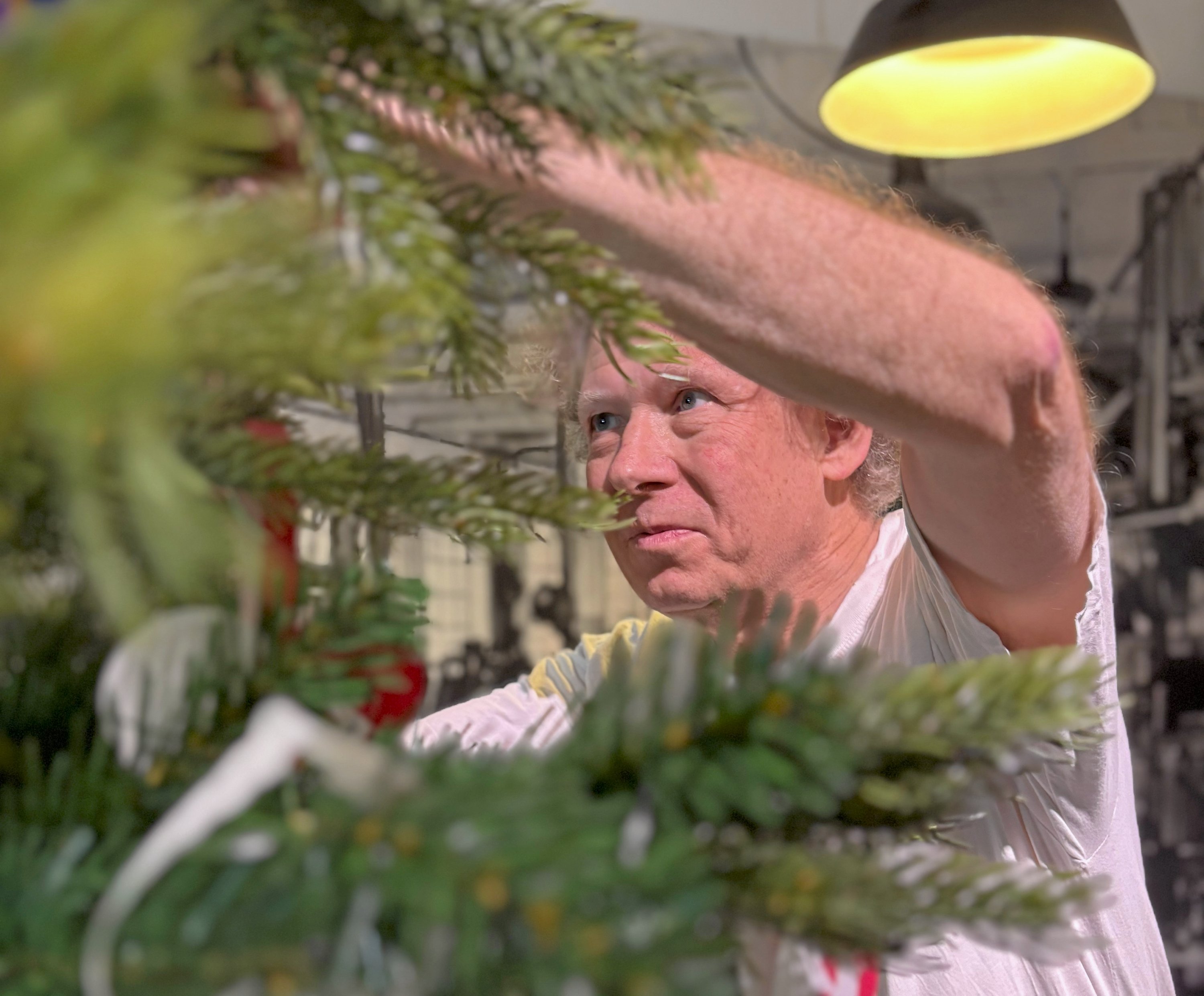 Her ses Leif Petersen, der er ved at pynte juletræet på første sal med et af sine mange tusind julehjerter. Han er danmarksmester i at flette julehjerter.