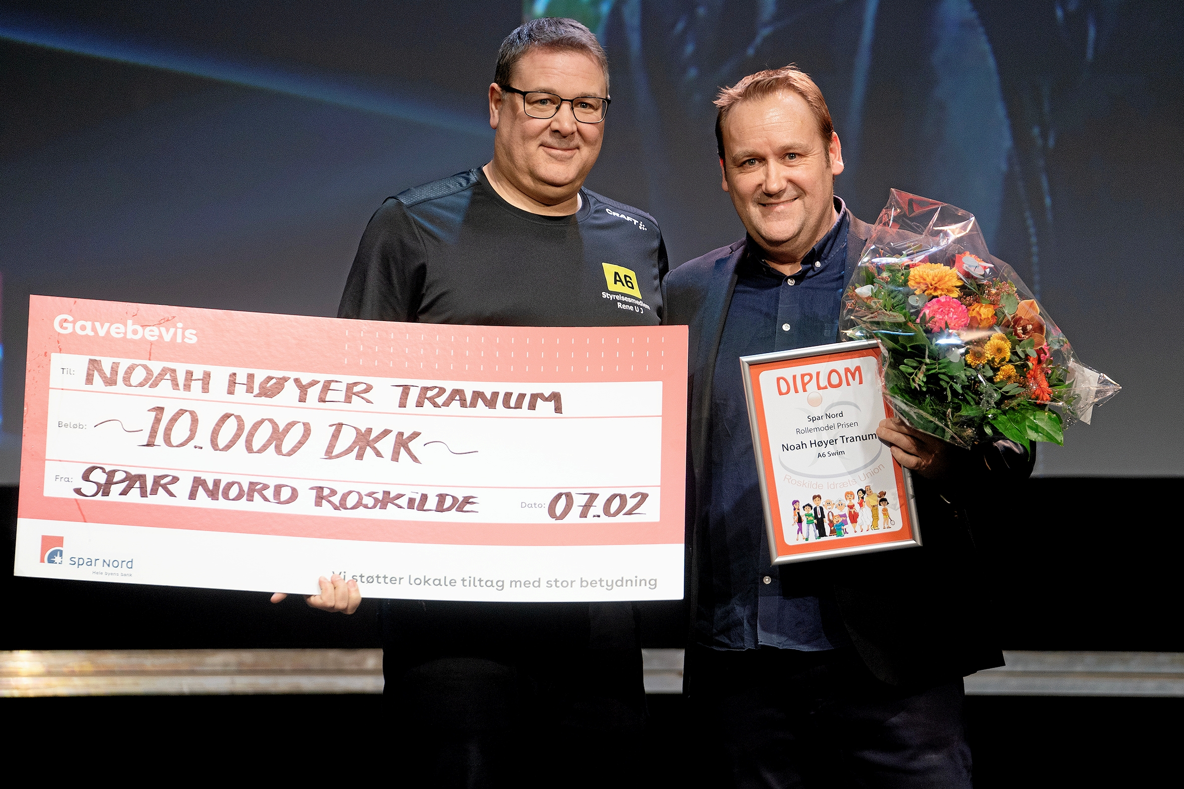 Noah Høyer Tranum fra A6 Swim kunne ikke modtage Spar Nords Rollemodelpris, da han er på træningslejr i Tyrkiet. I stedet var René Uldall-Jessen fra A6 Styrelsen på scenen sammen (tv) med Spar Nord-direktør Jesper Henriksen. - Thomas Olsen Noah Høyer Tranum fra A6 Swim kunne ikke modtage Spar Nords Rollemodelpris, da han er på træningslejr i Tyrkiet. I stedet var René Uldall-Jessen fra A6 Styrelsen på scenen sammen (tv) med Spar Nord-direktør Jesper Henriksen.