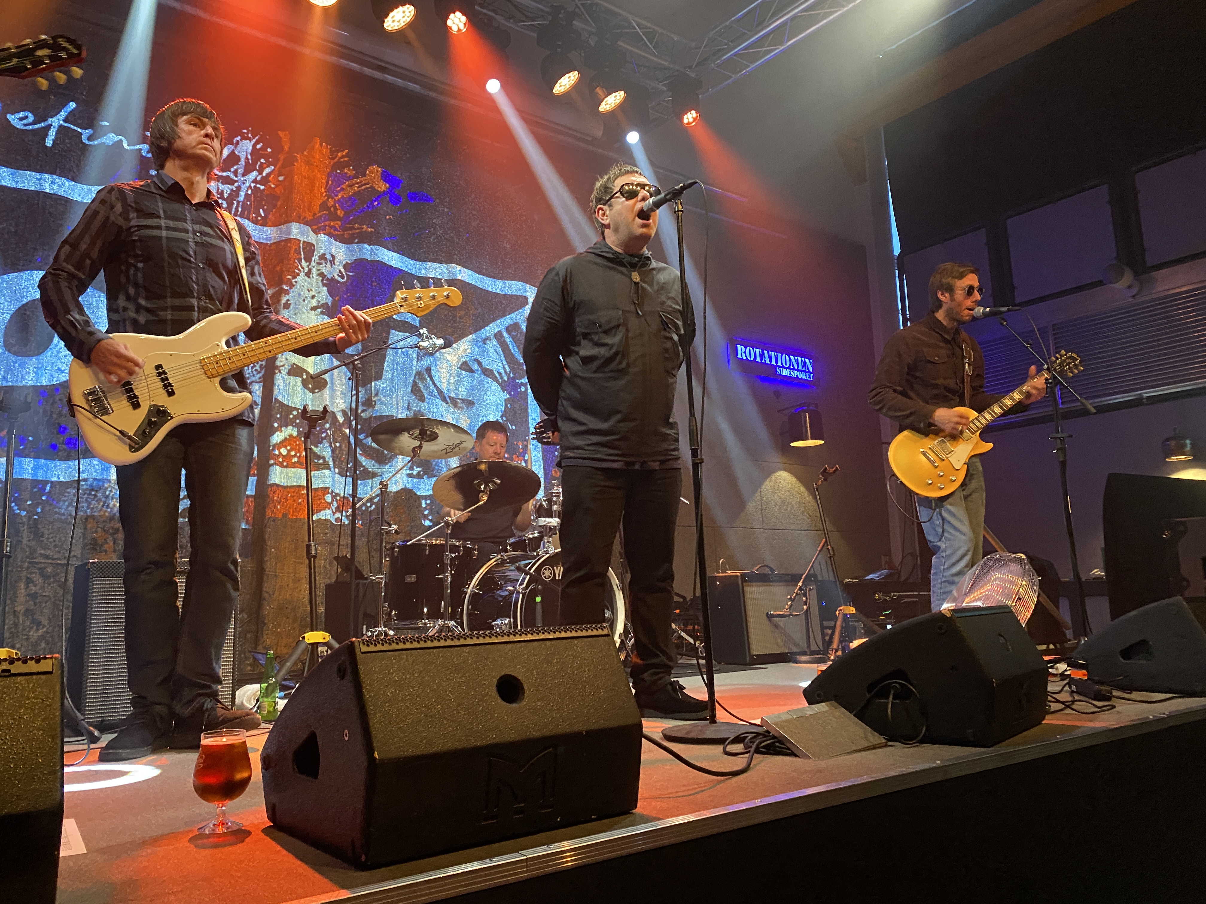 Brian McGhee førte an i rollen som Liam Gallagher – inklusive anorak og hænderne på ryggen. Til venstre bassisten Fraser Malcolm, i baggrunden Liam O'Hare bag trommerne. Og til højre har Steve Cole rollen som Noel Gallagher.