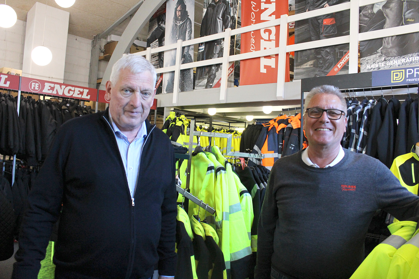Indehaver Poul Erik Pedersen (til venstre) har drevet Holbæk Firmatøj siden starten i 1995. I dag servicerer butikken over 500 faste erhvervskunder med arbejdstøj og firmalogoer.
