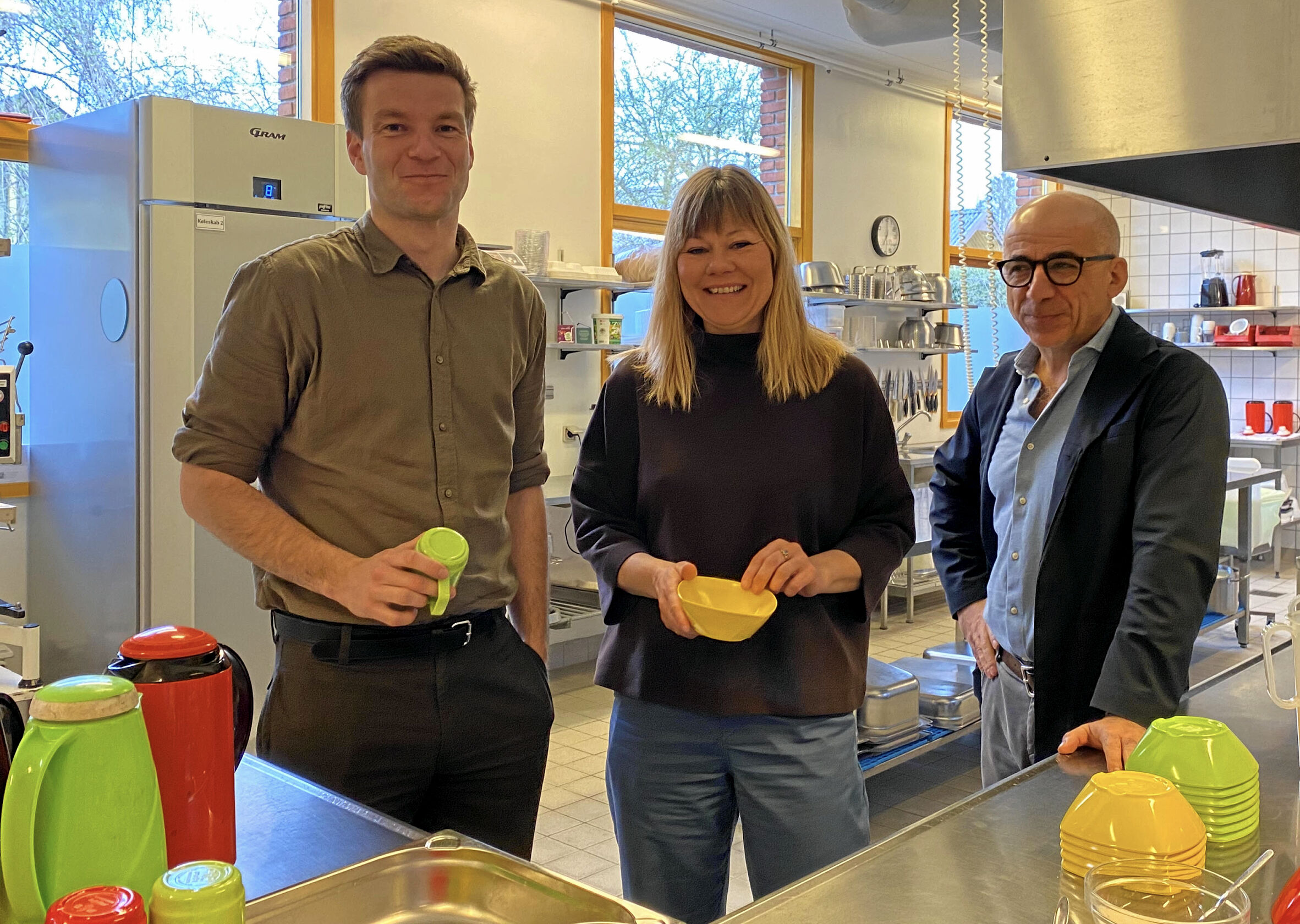Sigurd Agersnap, folketingsmedlem (SF) og Vivi Nør Jacobsen, kommunalbestyrelsesmedlem (SF) og skoleleder Yasar Cakmak bag serveringsdisken ved morgemad på Herstedvester Skole.