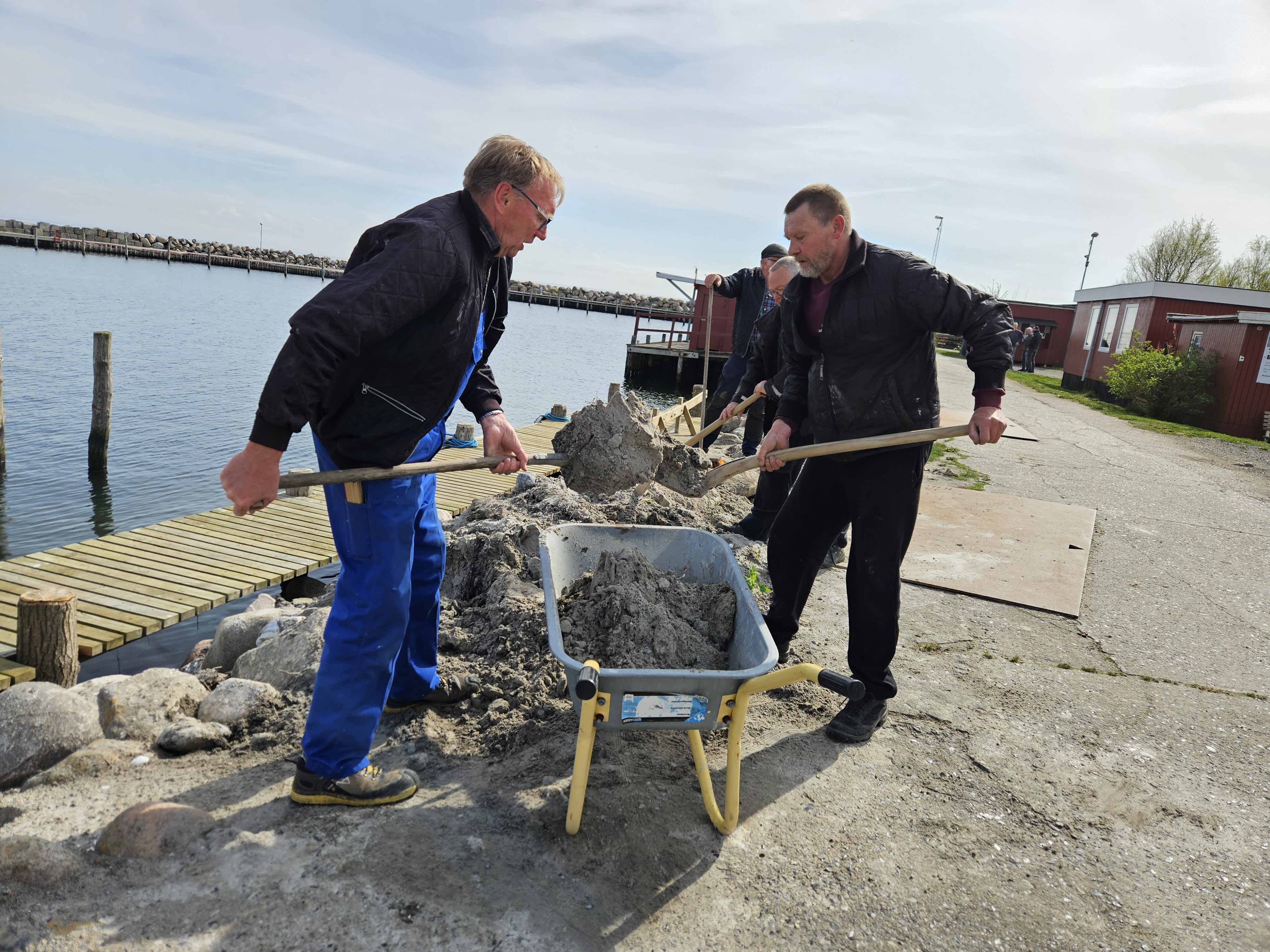Onsdagsgruppen har hele tiden mere at lave på havnen. Her fyldes der sand mellem de store kampesten.