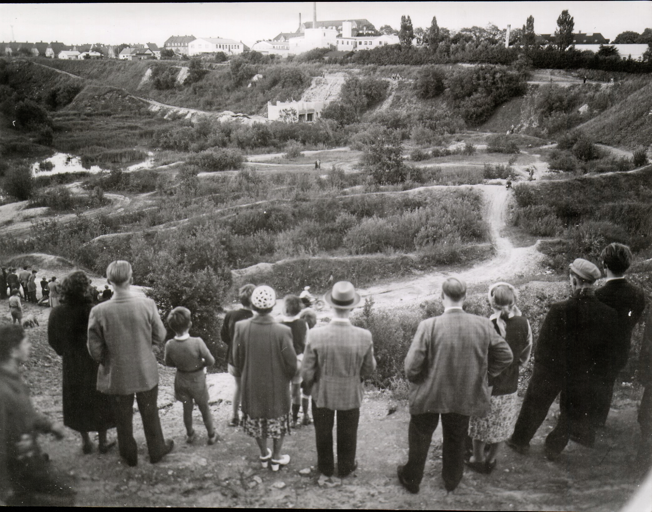 Kan det virkelig blive til Skandinaviens første motorsportsbane? Nysgerrige borgere betragter i august 1954 anlæggelsen af Roskilde Ring i den nedlagte grusgrav. Man kan desuden følge arbejdet i Roskilde Tidende. "Støjen fra Motorvognene kan ikke høres uden for Grusgraven. Det bliver Danmarks første lydløse Bane," lyder det lovende fra arrangørerne i avisen.