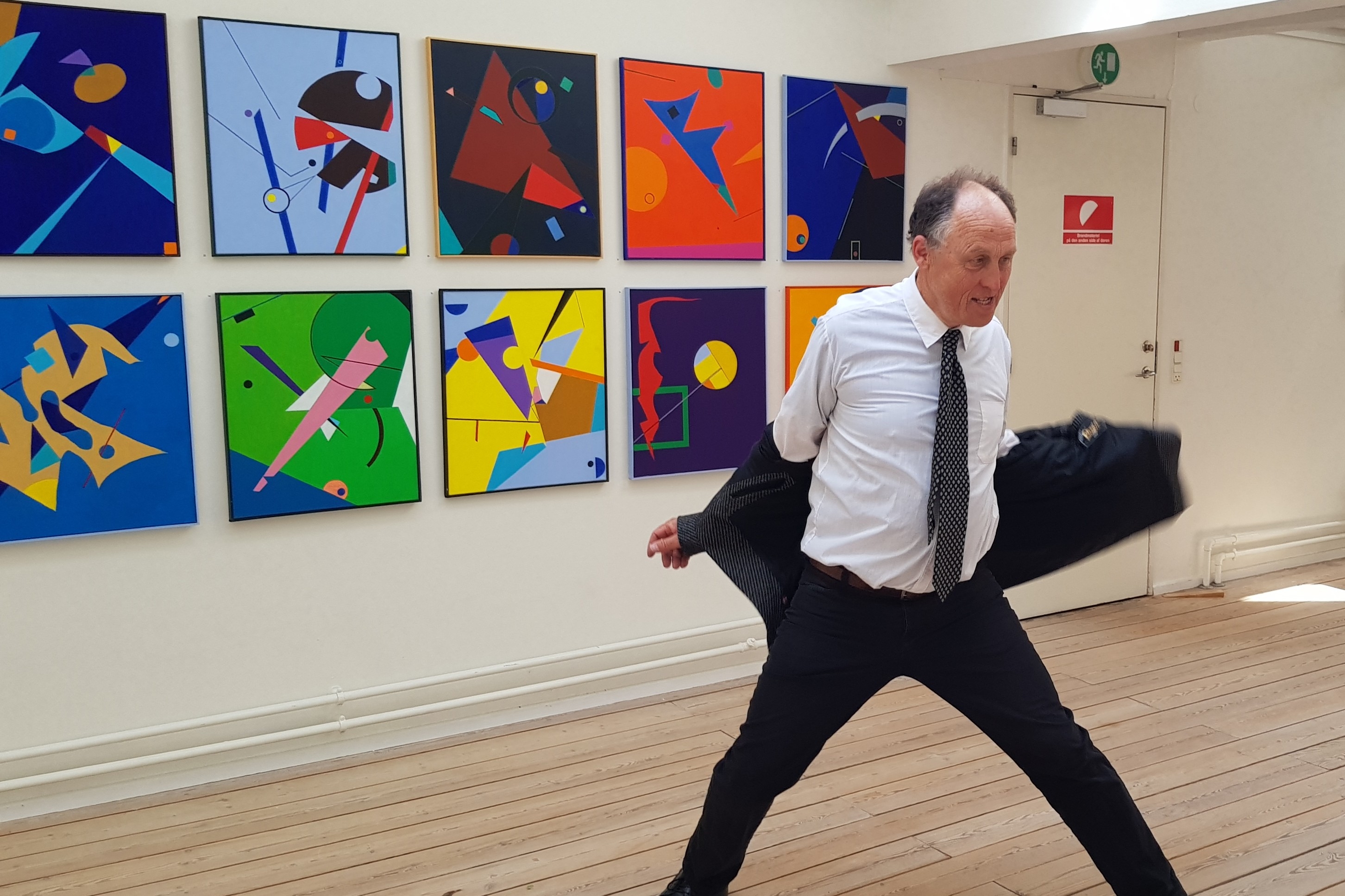 Billedkunstner Morten Nyhus fra Stokrosebanden i en vild jakke-performance foran malerier af Per Johan Svendsen.