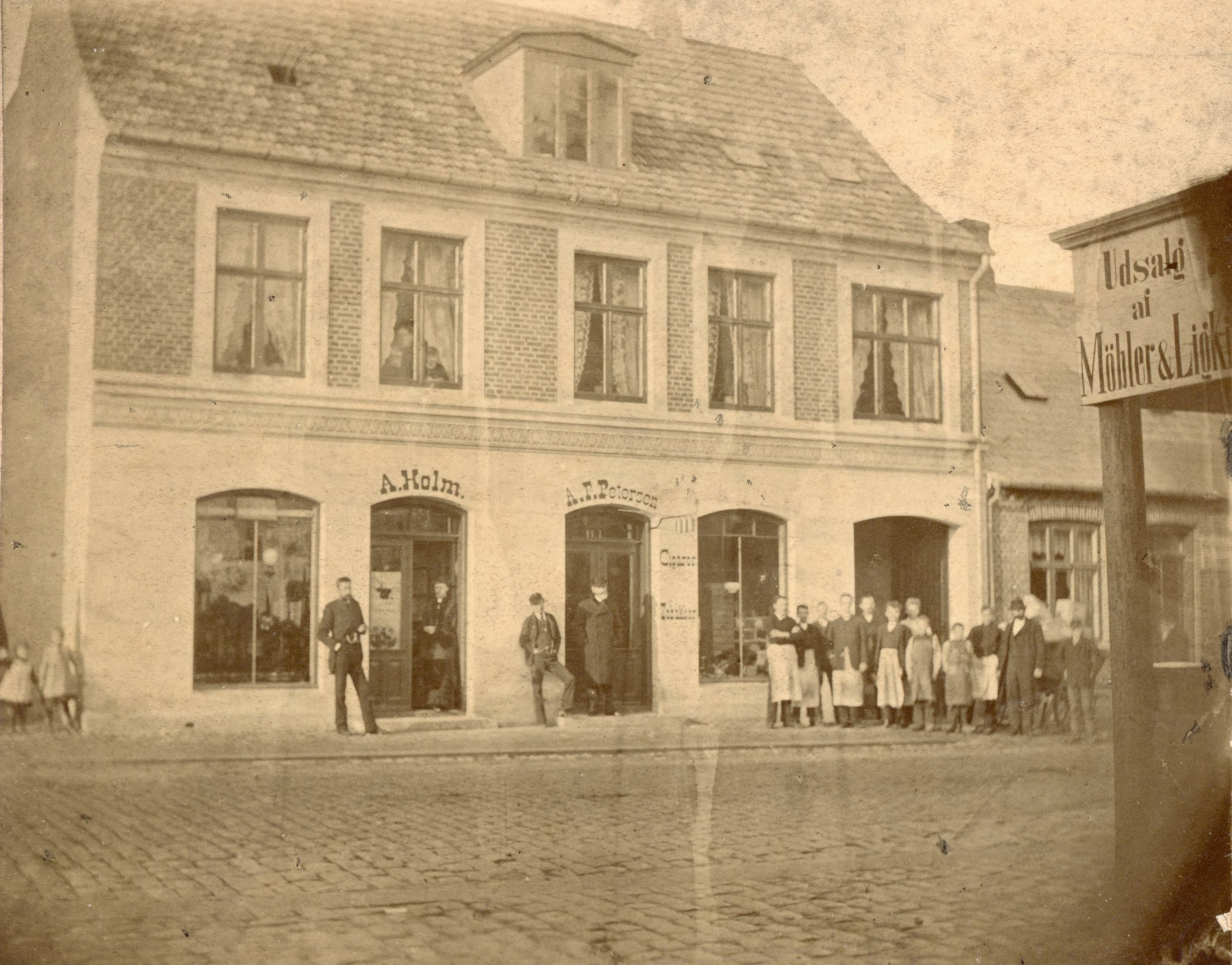Et fotografi fra 1890 af Slotsgade 51 med tobaksfabrikkens personale foran porten til højre. Personen i døren til butikken er formentlig A.F. Petersen selv. - Lokalhistorisk Arkiv Hillerød Et fotografi fra 1890 af Slotsgade 51 med tobaksfabrikkens personale foran porten til højre. Personen i døren til butikken er formentlig A.F. Petersen selv.