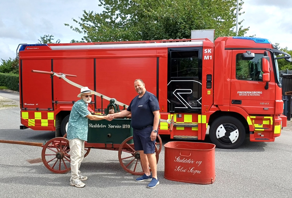 Henrik Schlytter (tv) får den historiske Skuldelevsprøjten (foran brandbilen). - Nu må I ikke udkonkurrere os, lød hilsenen fra Skibby Brandstation. - Privat Henrik Schlytter (tv) får den historiske Skuldelevsprøjten (foran brandbilen). - Nu må I ikke udkonkurrere os, lød hilsenen fra Skibby Brandstation.