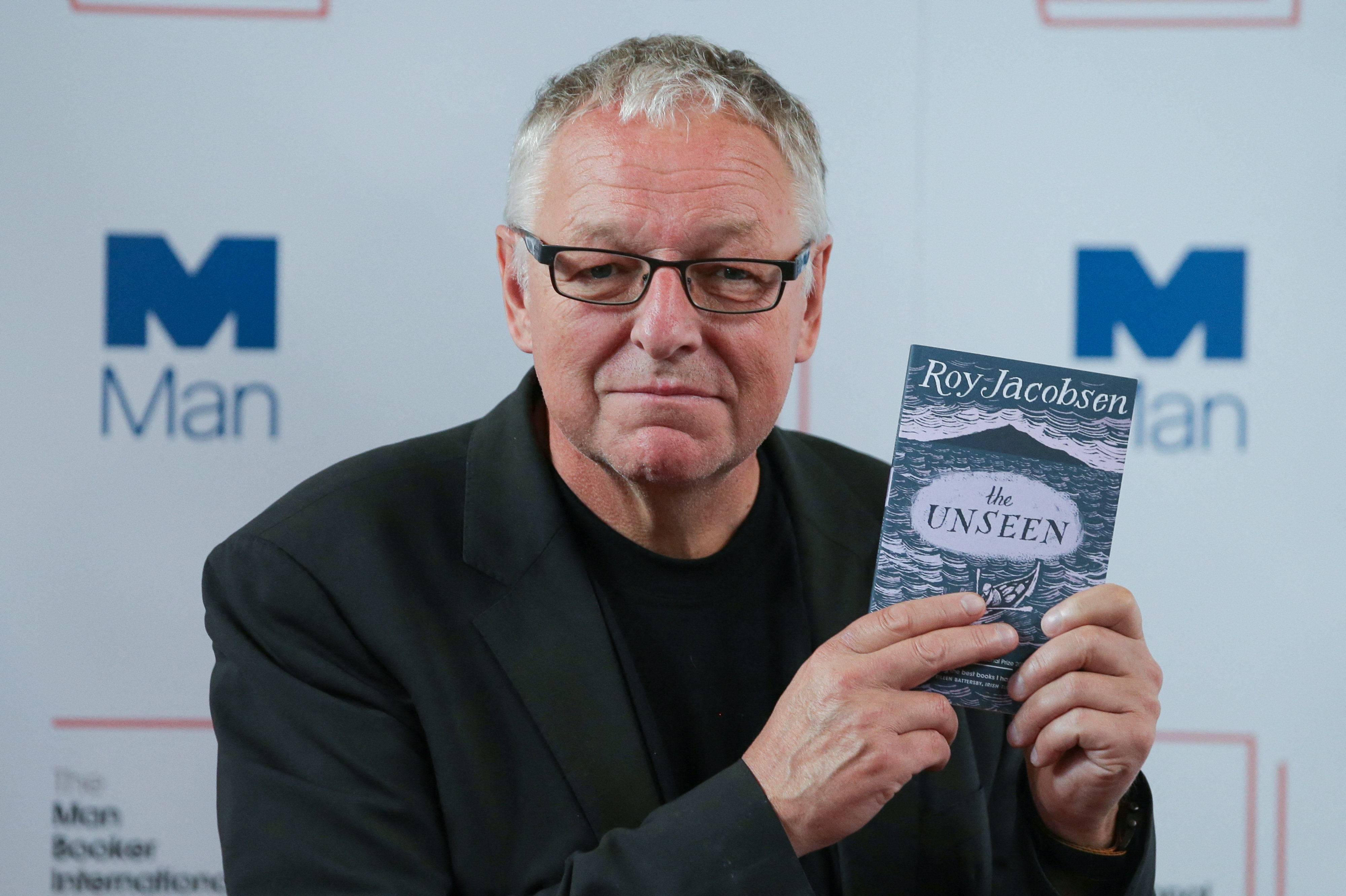 Den norske forfatter Roy Jacobsen poserer med sin bog "The Unseen", der har den norske titel "De usynlige", ved en konference i London i 2017. (Arkivfoto).
