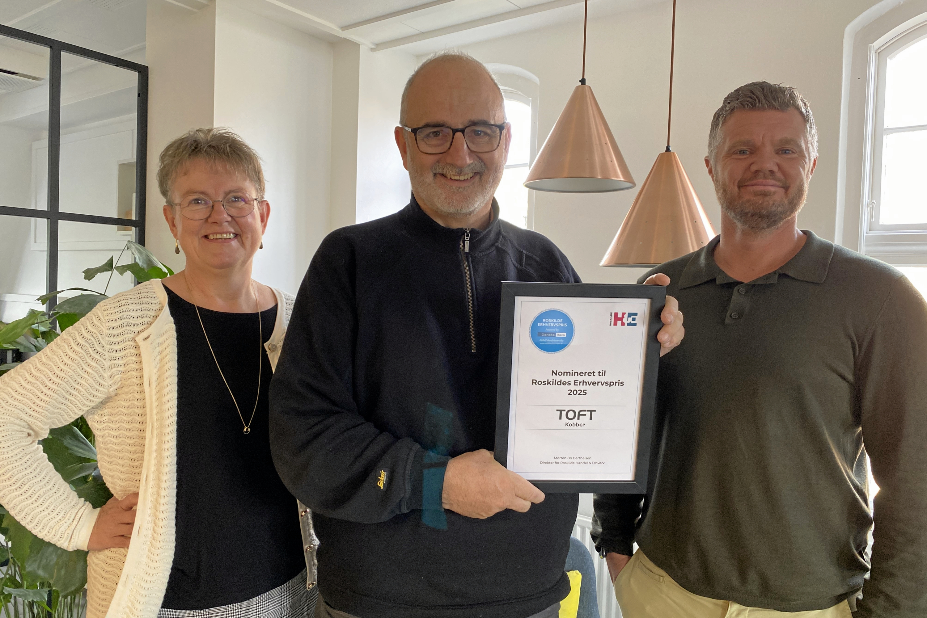 Toft Kobber er nomineret til Roskilde Erhvervspris. Stifter og administrerende direktør Brian Toft (midten) ses med Lone Alexandersen fra Danske Bank og Nikolaj B. Worch fra Roskilde Handel & Erhverv. Lamperne i baggrunden er ikke lavet af Toft Kobber.