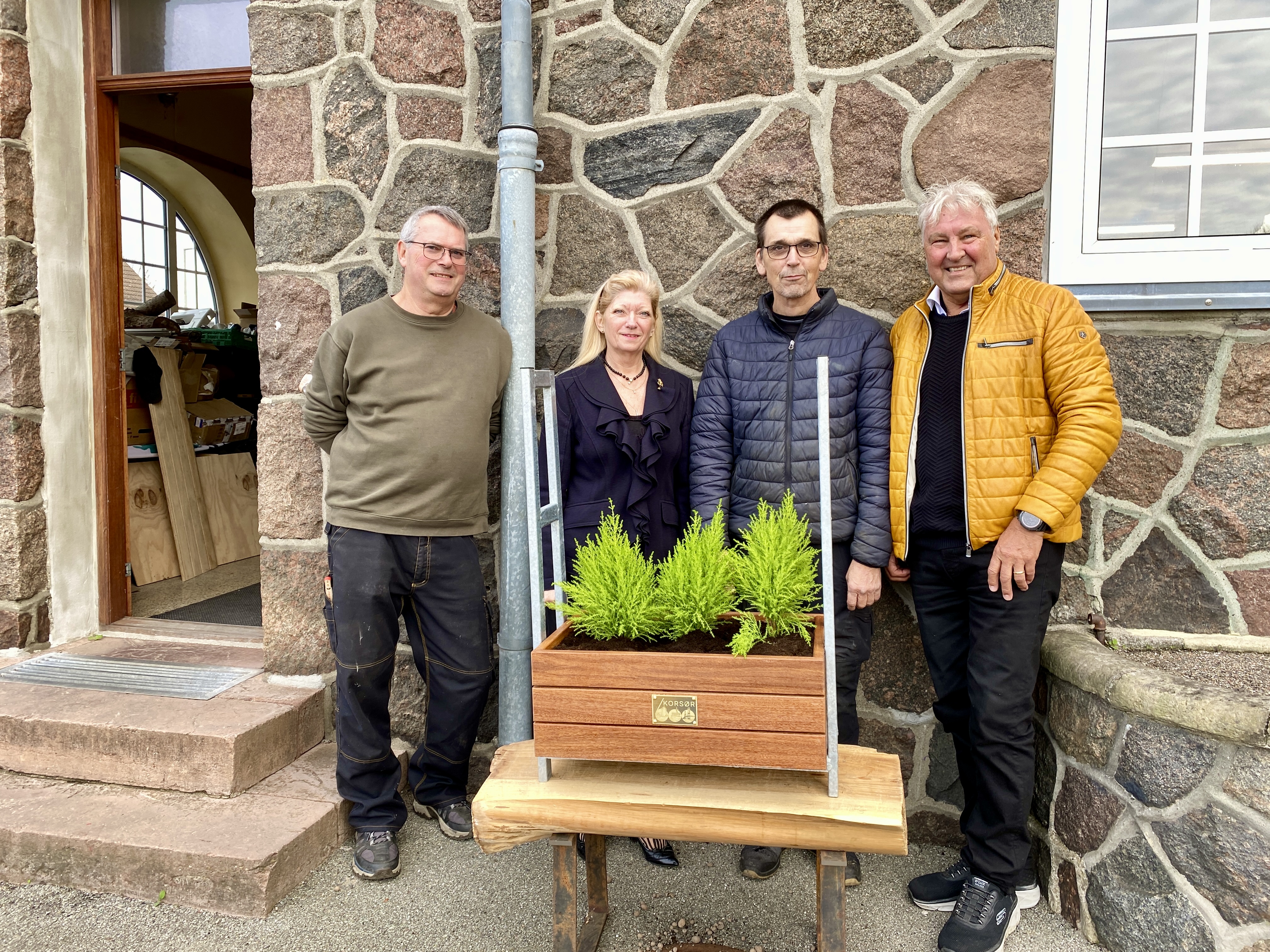 Kim Fabritius de Tengnagel, Lotte Brøns, Lars Dilby og Troels Christensen med en af de 52 plantekasser, som medlemmer af Mænds mødested Korsør har bygget. Blomsterkasserne er siden blevet opstillet foran en række forretninger i Korsør. De skal nu have et indhold af blå, gule og hvide blomster.