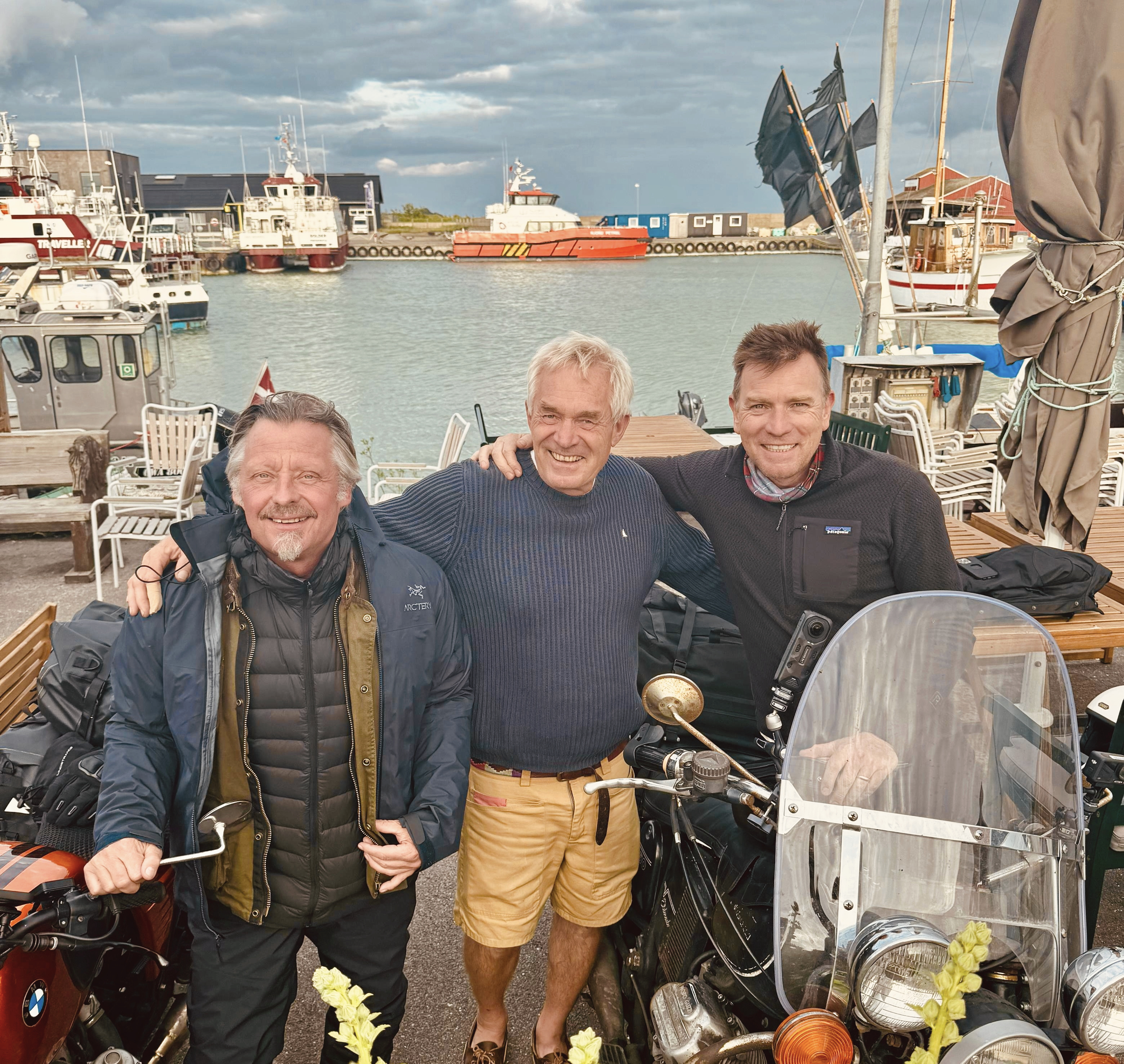 Hollywood-stjernerne Ewan McGregor og Charley Boorman på besøg hos Ole Eskling og café "Klap Hesten". I baggrundende ses de Crew Transfer Vessels, der hver dag sejler mandskab ud fra Klintholm Havn.