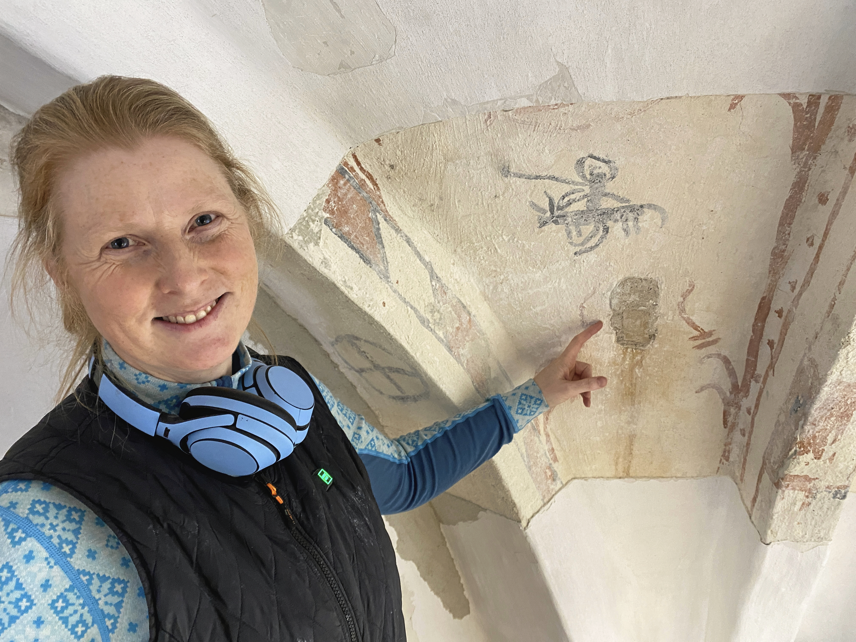 Konserveringstekniker ved Nationalmuseet Camilla Ipsen peger på det såkaldte sladderhul. Ovenover er en mand og et dyr malet.