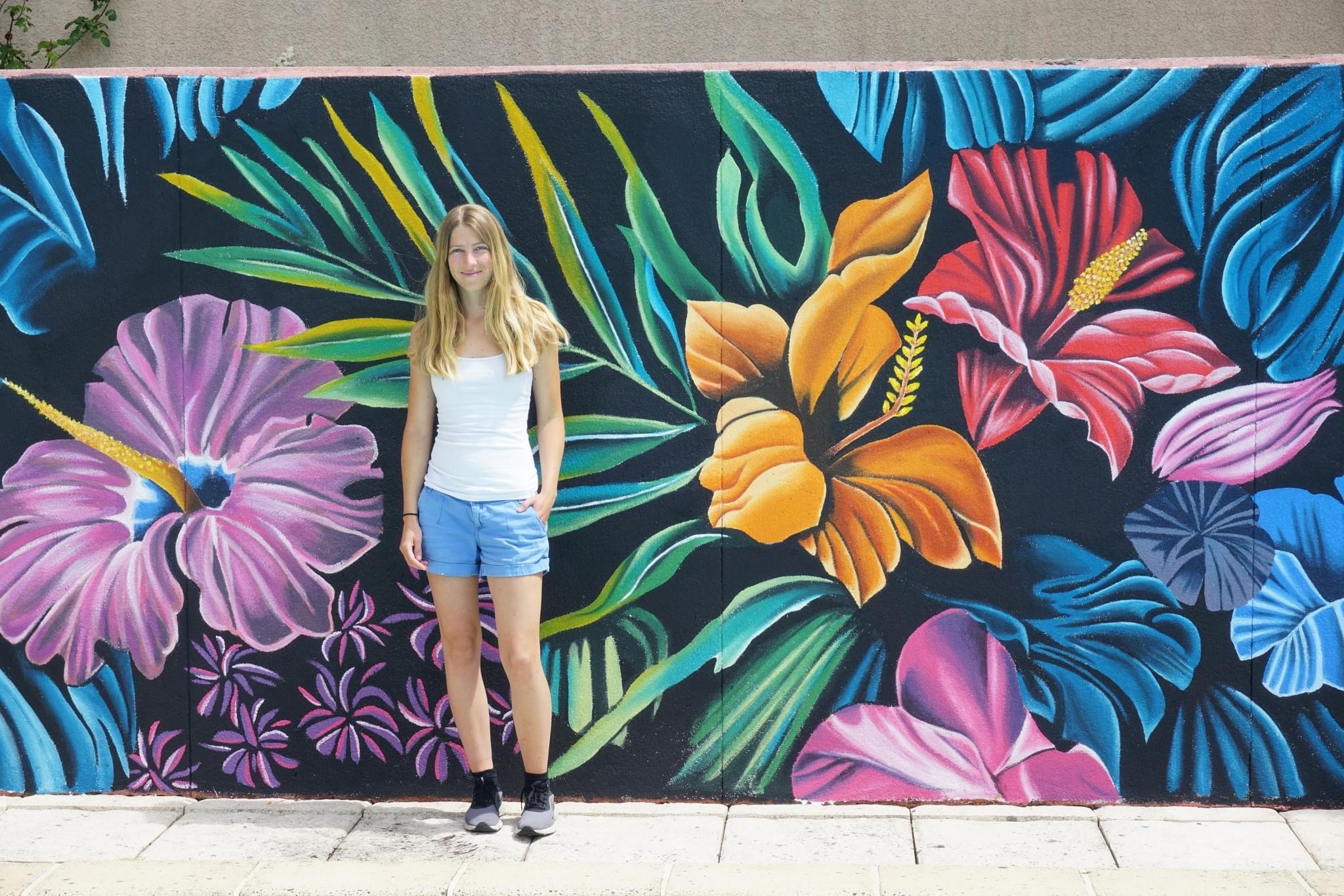 Annika Thue Jensen er kunstmaler i stort format. Hun har rødder i Roskilde og vil gerne give et gavlmaleri gratis til byen på et offentligt sted. Her står hun foran et maleri, hun lavede i Nice i 2024.