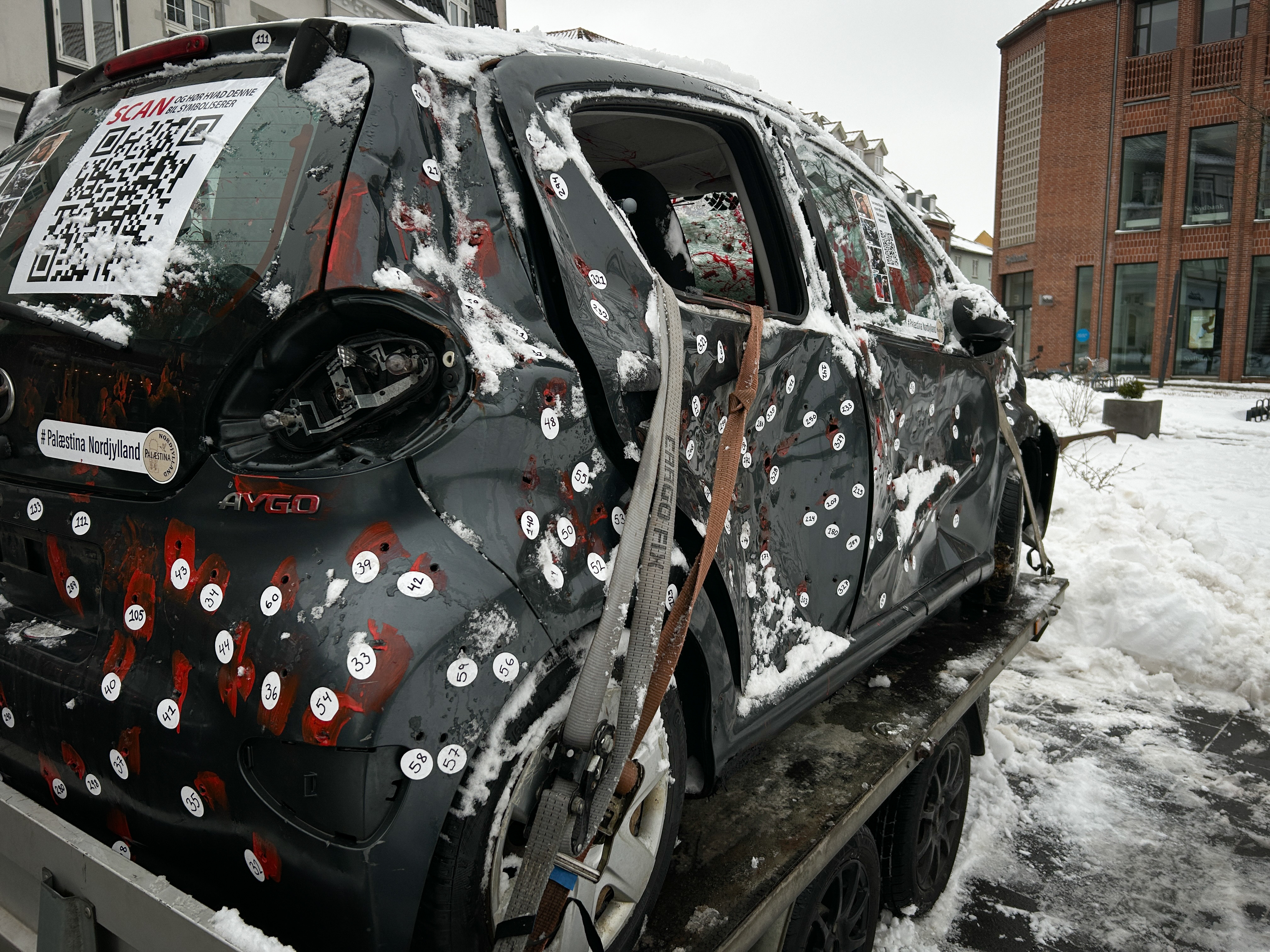 Bilen, som kommer til at stå på Nytorv i Store Heddinge, har tidligere været udstillet på Schweizerpladsen i Slagelse. Den er oprindeligt lavet af en af Palæstina Initiativets afdelinger i Nordjylland, hvor den har været udstillet i Aalborg, Aarhus og senest i Ringsted i forbindelse med udgivelsen af spillefilmen.