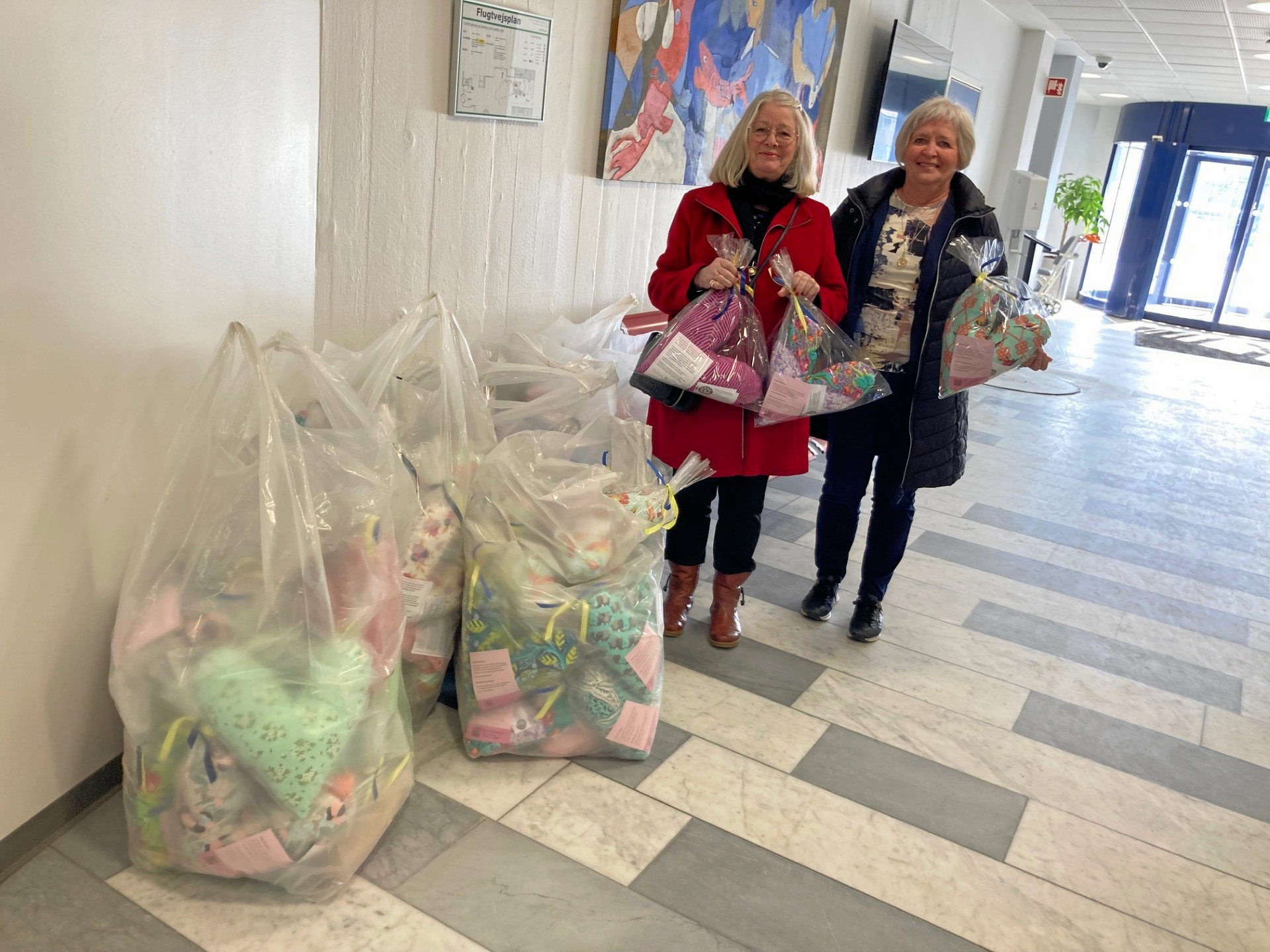 På billedet ses Soroptimisterne i Slagelses præsident, Kirsten Stick, og soroptimist, Berit Madsen, ved afleveringen. Puderne bliver modtaget med stor glæde og taknemmelighed af både patienter og personalet på det onkologiske ambulatorium på Roskilde Sygehus.