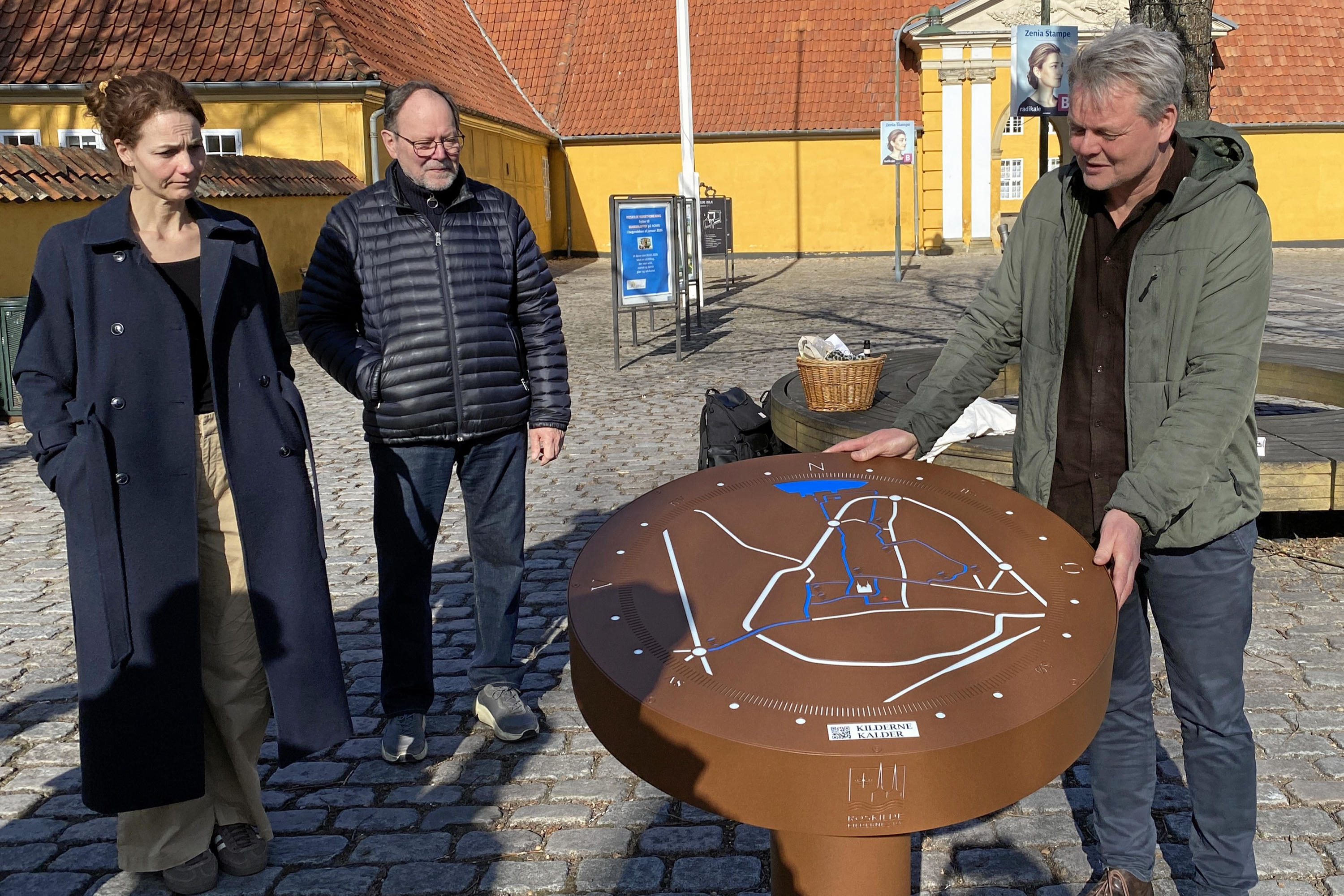 Jesper Tarnø (th) er designeren bag formidlingsstationen, der viser, hvor byens kilder er. Til venstre ses Sofie Myschetzky fra Projektstier og Frank Binderup fra Foreningen Roskilde Kildernes By.