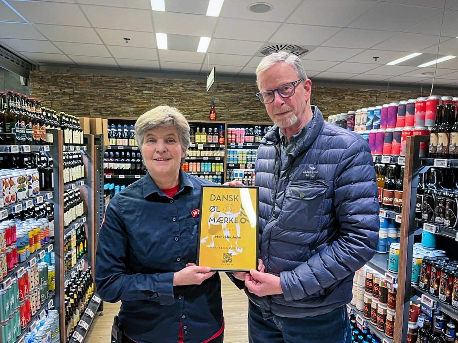 Meny Hørsholms ølsommelier og ølansvarlige, Dorte Jørgensen, får overrakt 'Dansk Ølmærke 2026' af Peter Kruse fra Danske Ølentusiaster i Birkerød.