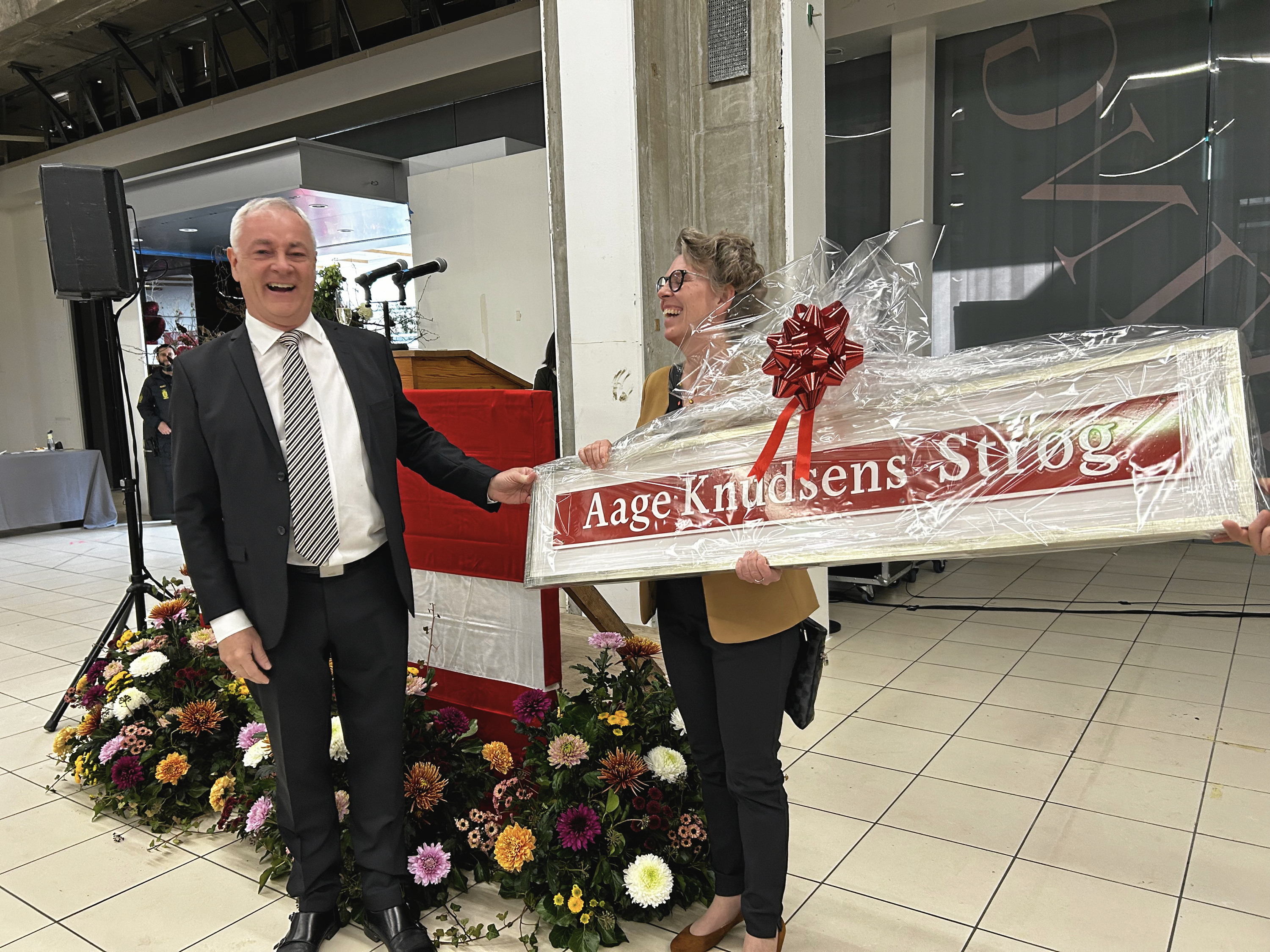 Rødovre Centrum modtager et originalt byskilt til Aage Knudsens Strøg af Rødovre Kommune i 60-års fødselsdagsgave. Centerets gave til byen var af en lidt anden kaliber.