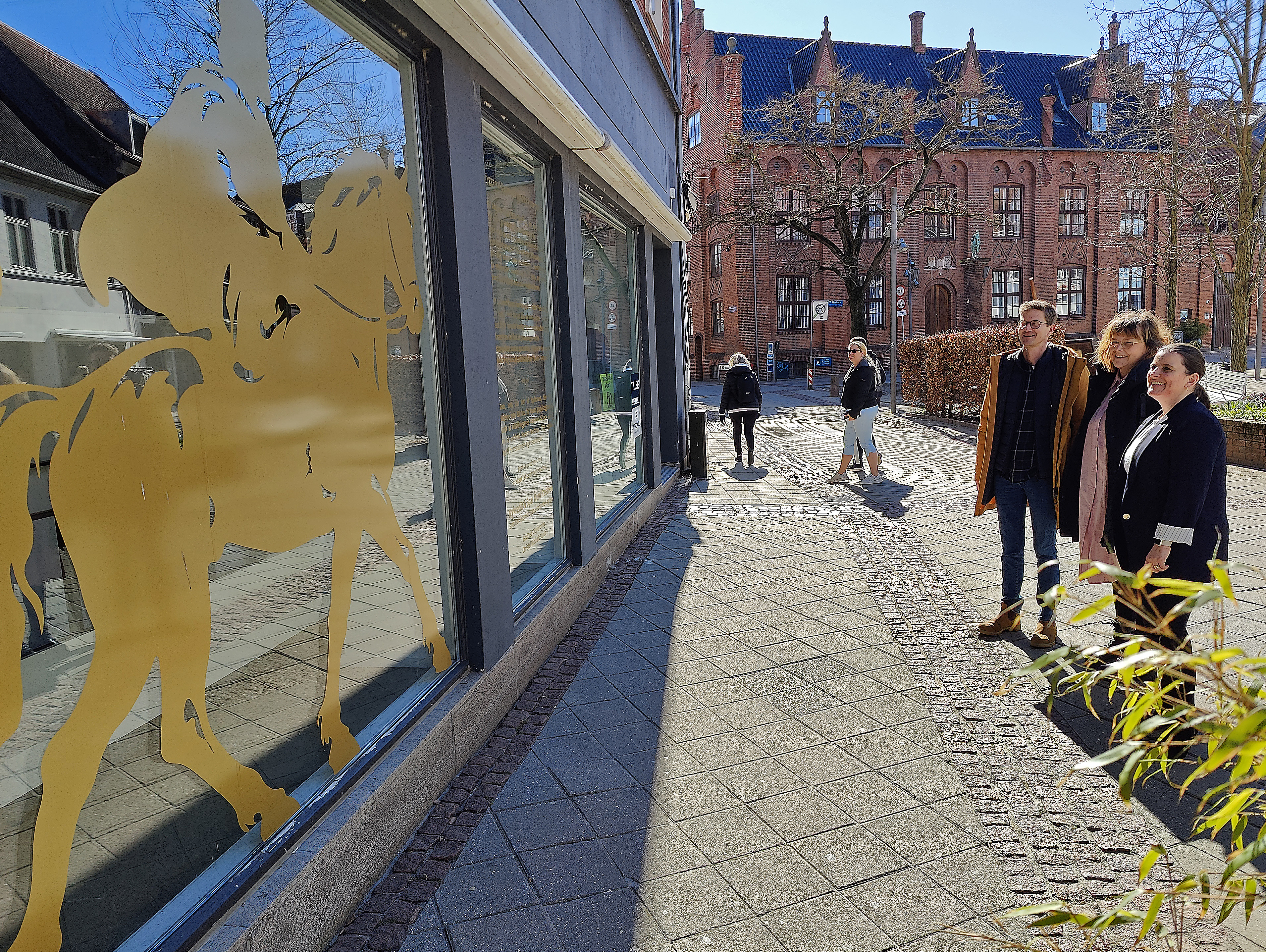 Den lille rytterstatue af Peder Bodilsen har endelig fået format. Her beundres den nye terning som folie på en ellers tom og trist butiksrude af citychef Nicolaj Lund Jensen, kunstner Christel Witthøft og bankdirektør Christina Birk Batsberg for den nye Lokal Bank Næstved.