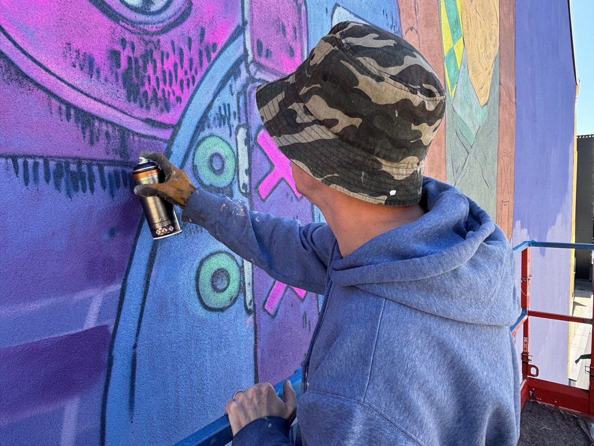 Elph fra Edinburgh er i disse dage ved at skabe Næstveds nyeste gavlmaleri. De sorte "dutter" kan være tegn på bevægelse eller slid. Der er mange detaljer i maleriet, så man kan godt bruge lidt tid på at stå og studere det.