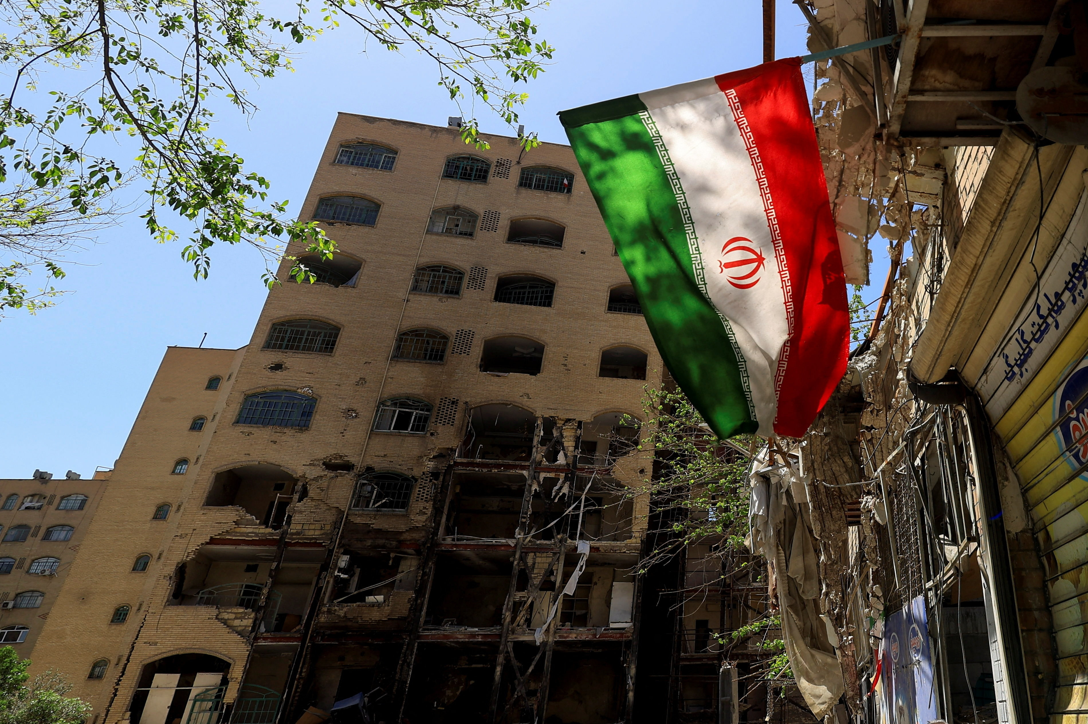 Et iransk flag kan ses nær en beboelsesbygning, som blev ødelagt i et angreb i begyndelsen af marts i den iranske hovedstad, Teheran. Billedet er fra 14. april.
