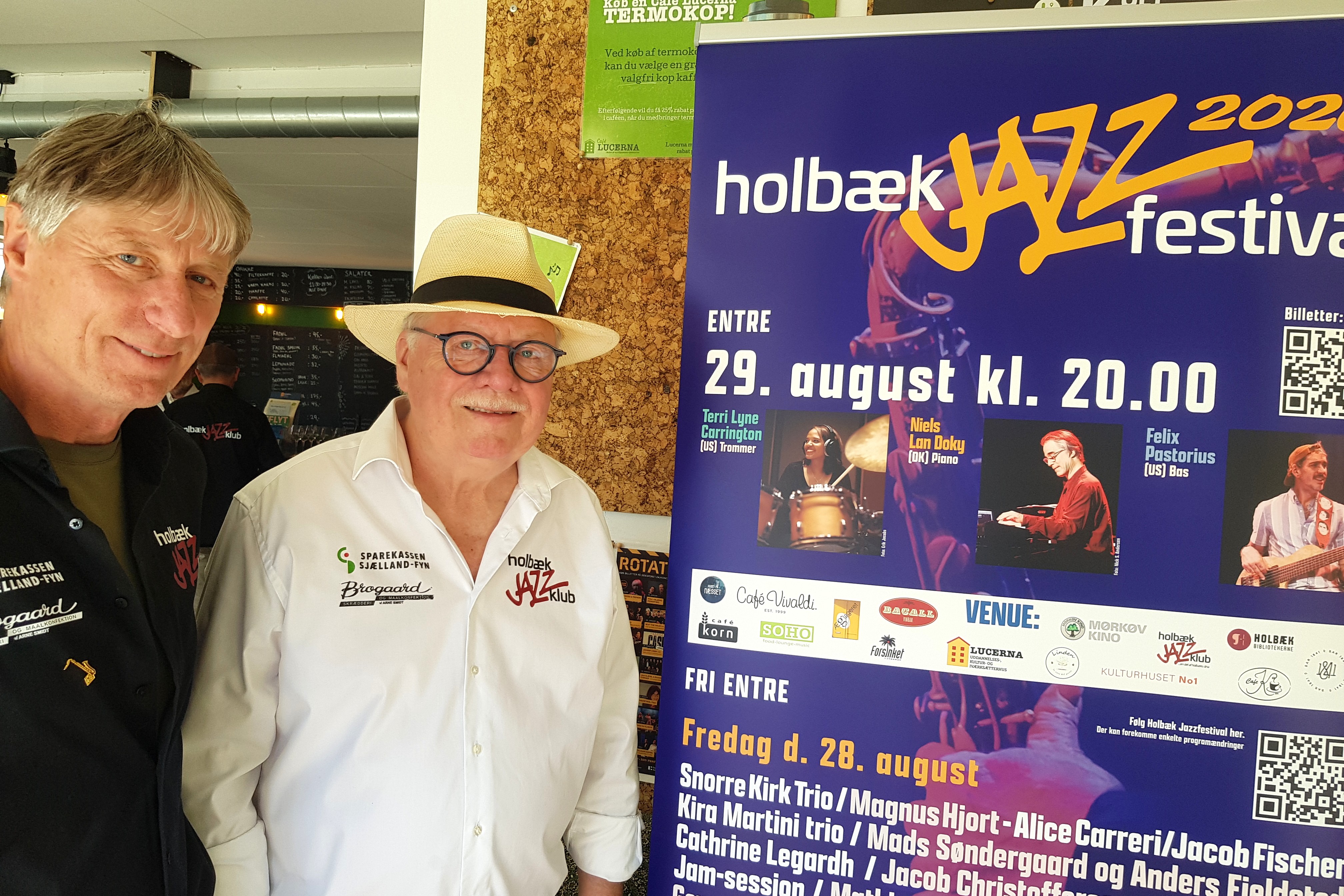 Michael Jurcenoks, (t.h.), formand for Holbæk Jazzklub, og næstformand Bjørn Hansen ved plakaten for Holbæk Jazzfestival 2026.
