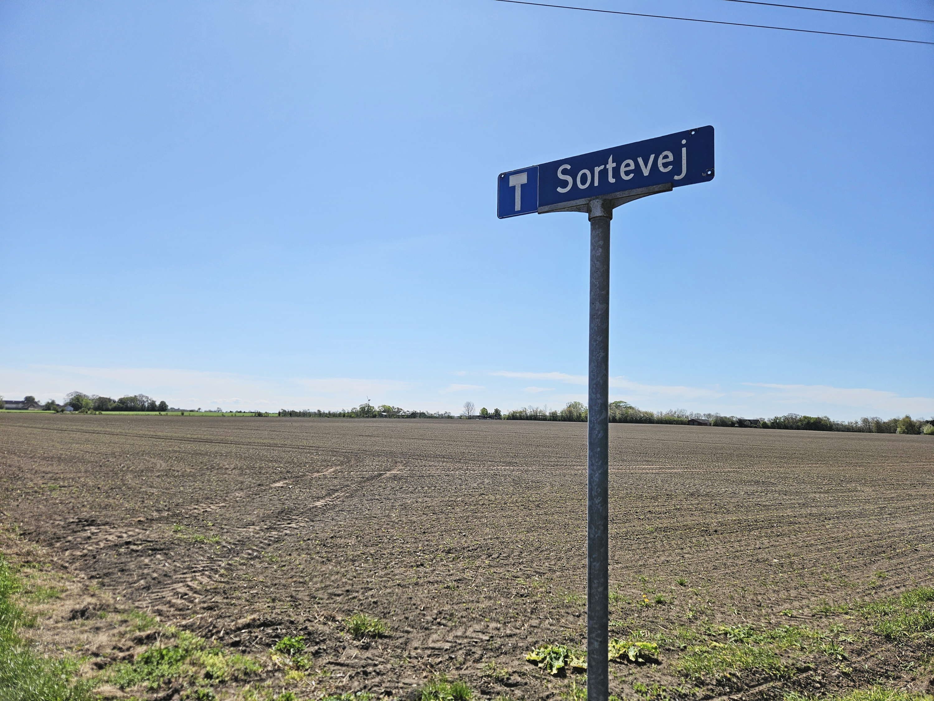 Sortevej, hvor ejendommene er inden for seks gange møllehøjdes afstand fra den potentielle placering af møllerne i Projekt Storemark. Yderst til venstre i baggrunden anes Storemarksgård, hvor møllerne ville skulle stå.