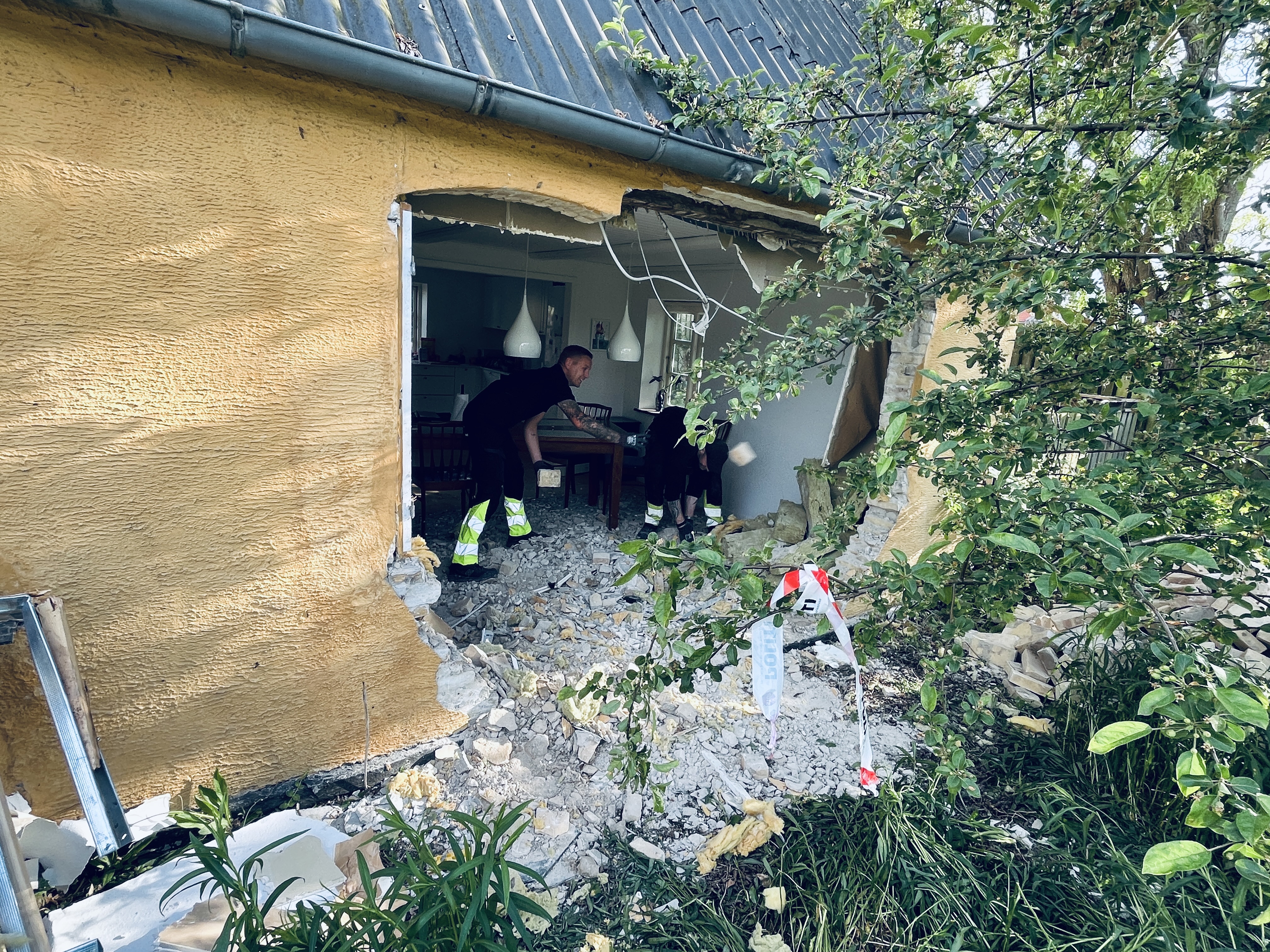 Huset fik nogle seriøse skader, efter at bilen bragede ind i det. Mændene på billedet er fra det firma, der er kaldt ind for at rydde op.