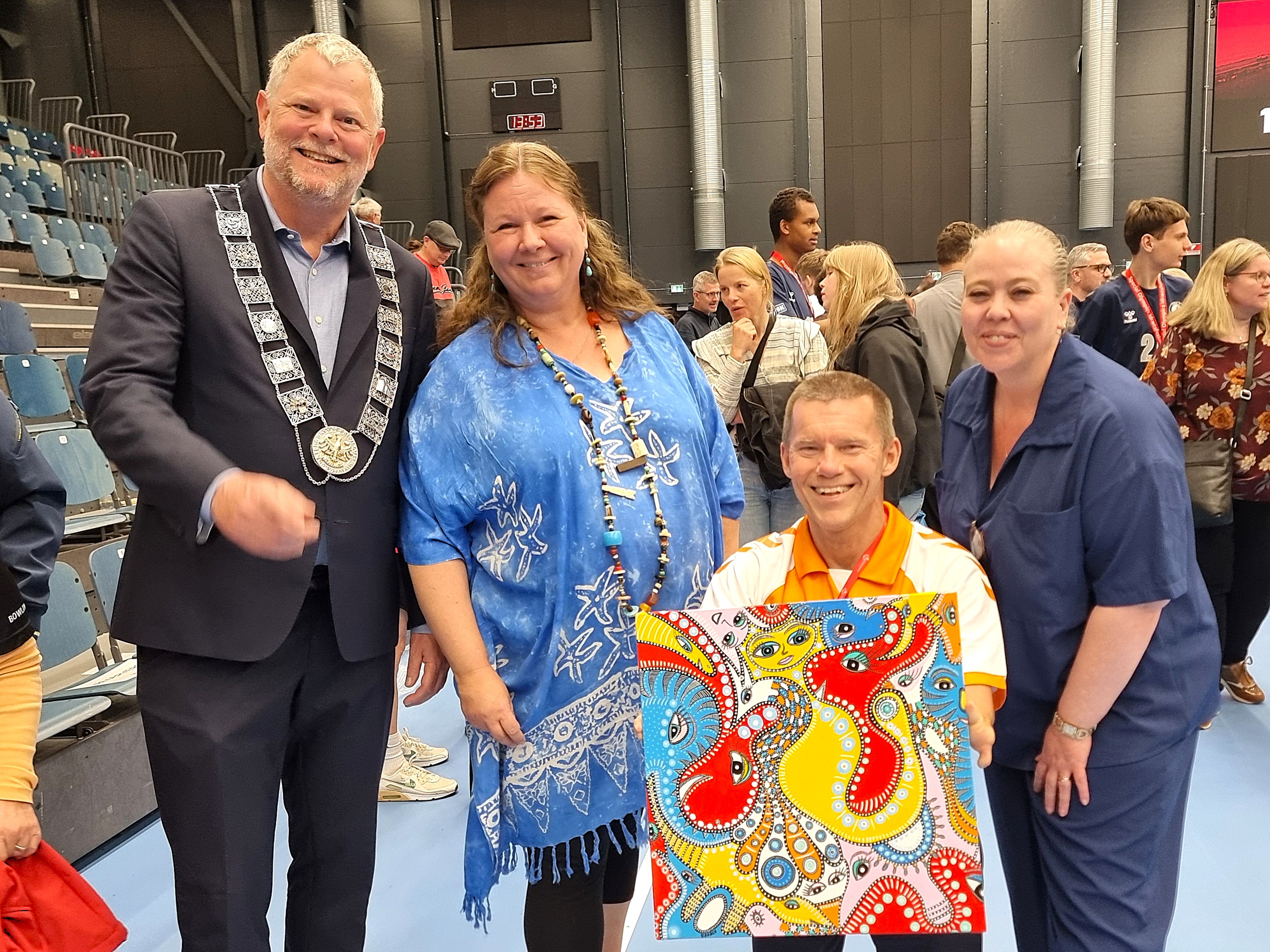 Her ses Furesø-kunstneren Bakaos sammen med Roskildes borgmester Tomas Breddam, Randers' borgmester Rosa Lykke Yde og John Petersson, formand for Parasport Danmark og Special Olympics Danmark, ved overdragelsen af værtskabet for Special Olympics Idrætsfestival 2028.