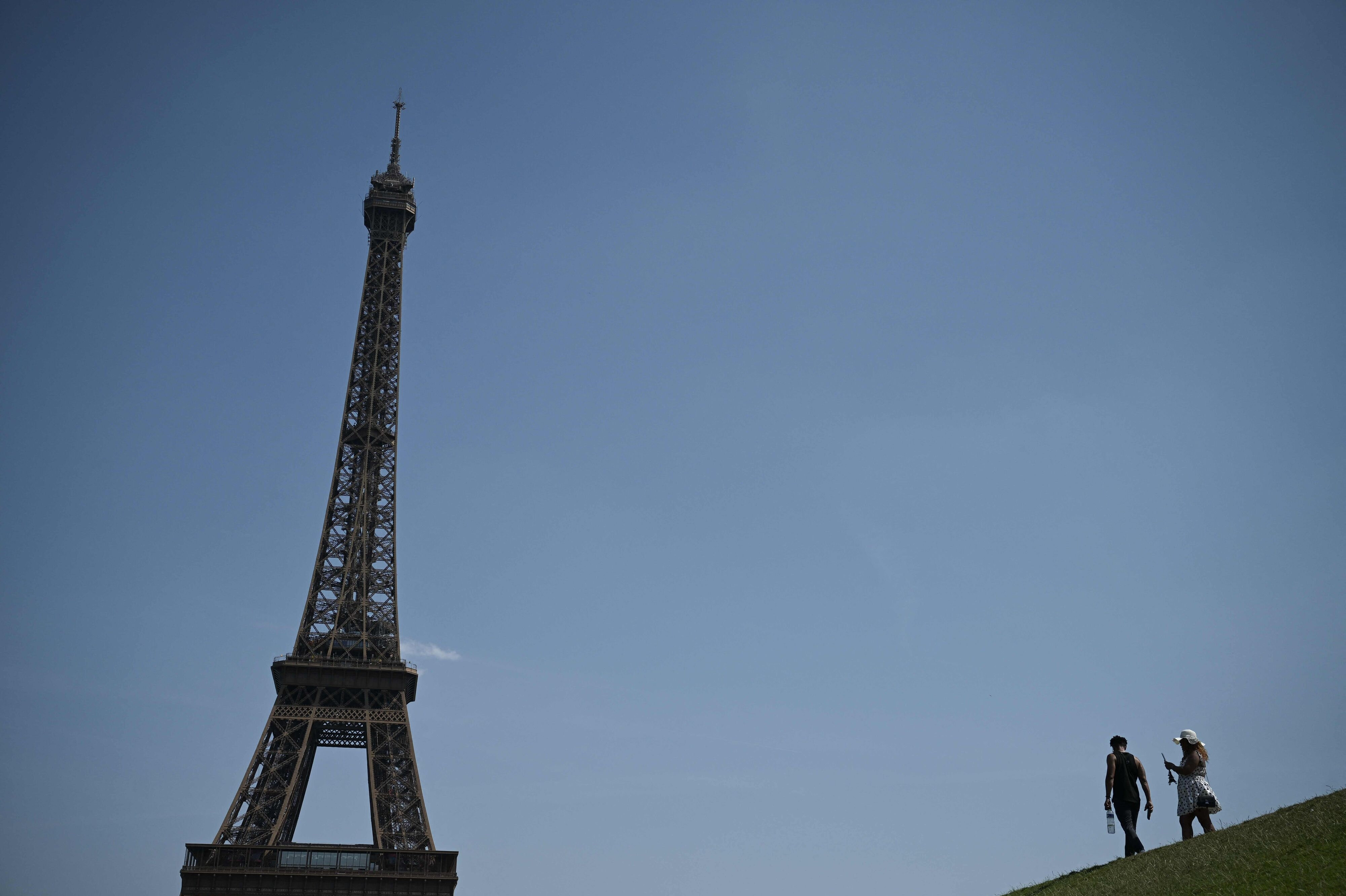 Folk går mandag med vandflasker nær Eiffeltårnet i Paris, mens høje temperaturer præger den franske hovedstad.