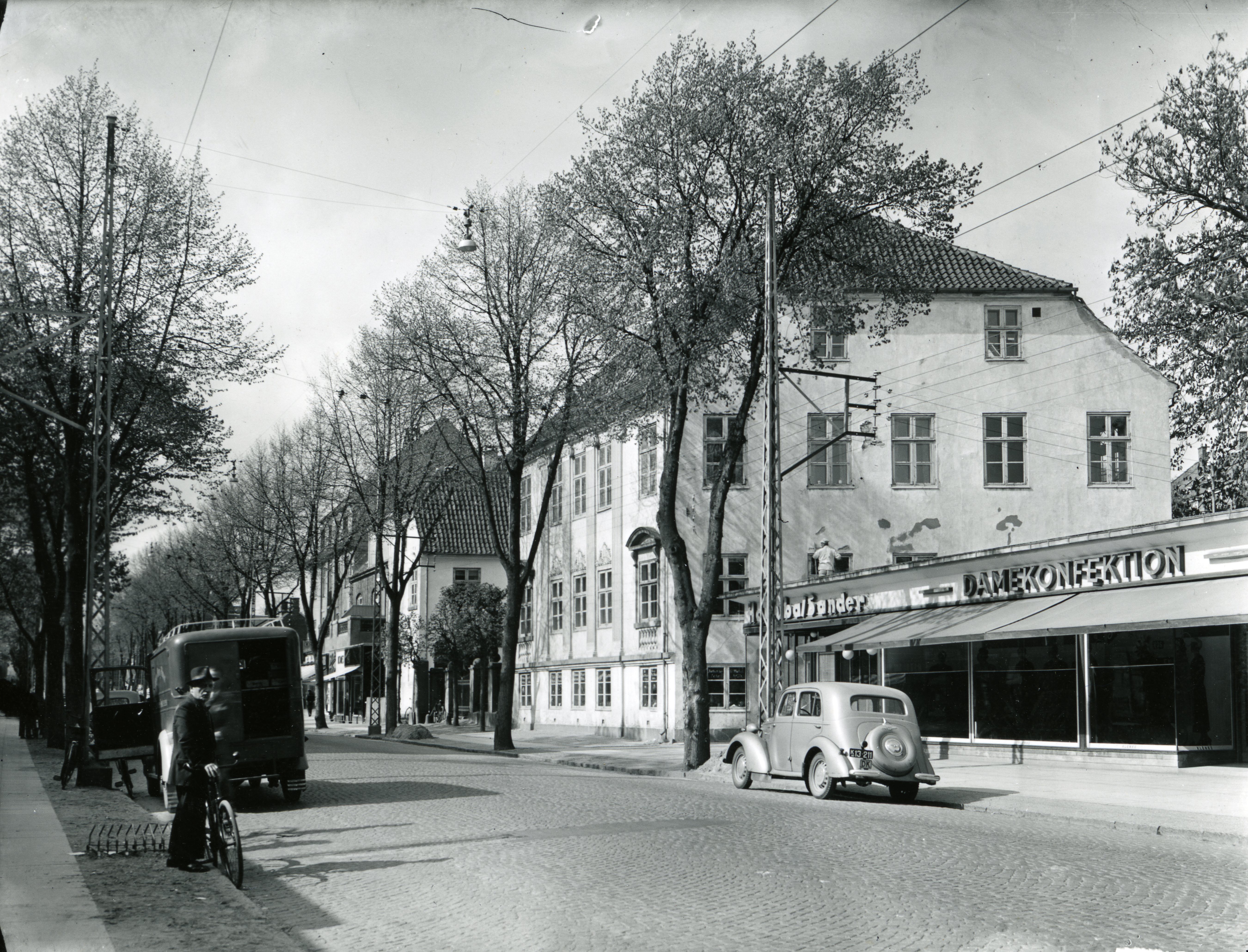 Det Hvide Palæ på Lyngby Hovedgade 37 med basarbygningen fra 1940 til højre, ca. 1950. Det er et af de ældste og flotteste huse i hovedgaden og stort set uændret gennem tiden. A/S Hanibal Sander Damekonfektion lå i Bazarbygningen i 1940-1970.