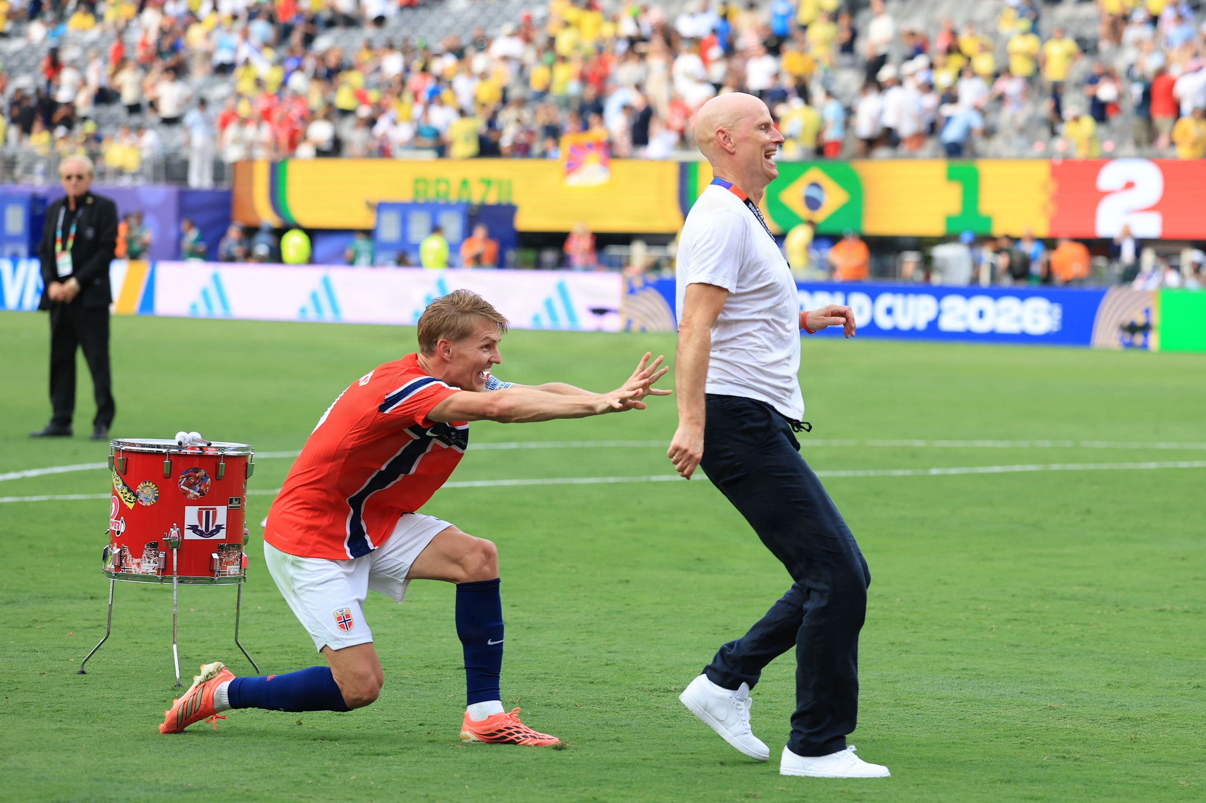 Anfører Martin Ødegaard skubber Ståle Solbakken hen mod en tribune med norske tilskuere efter 2-1-sejren over Brasilien.