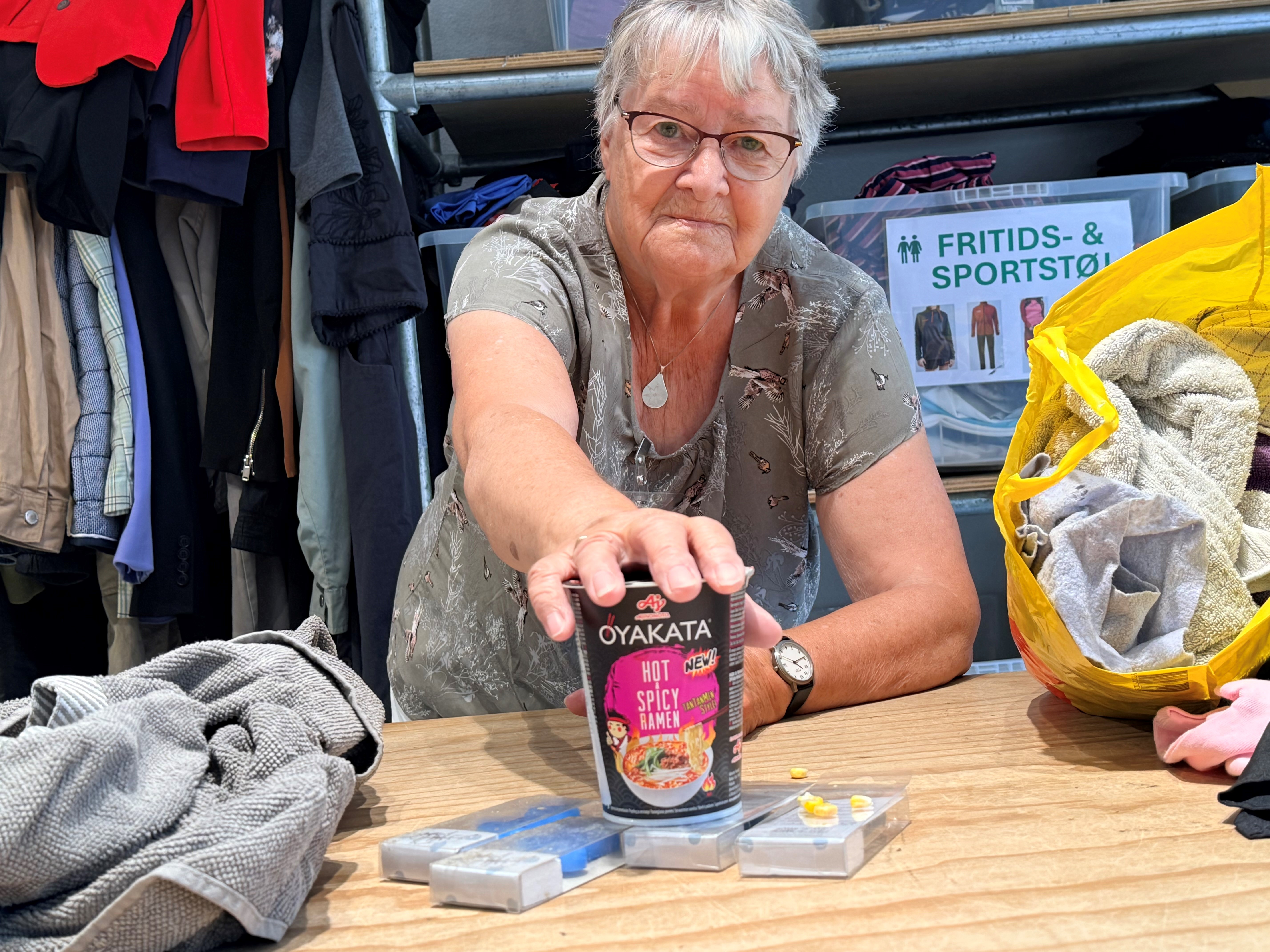 Kirsten Jensen med en halvtømt nudelkop med ramen og andre ting, der ikke hører hjemme i en tøjcontainer.