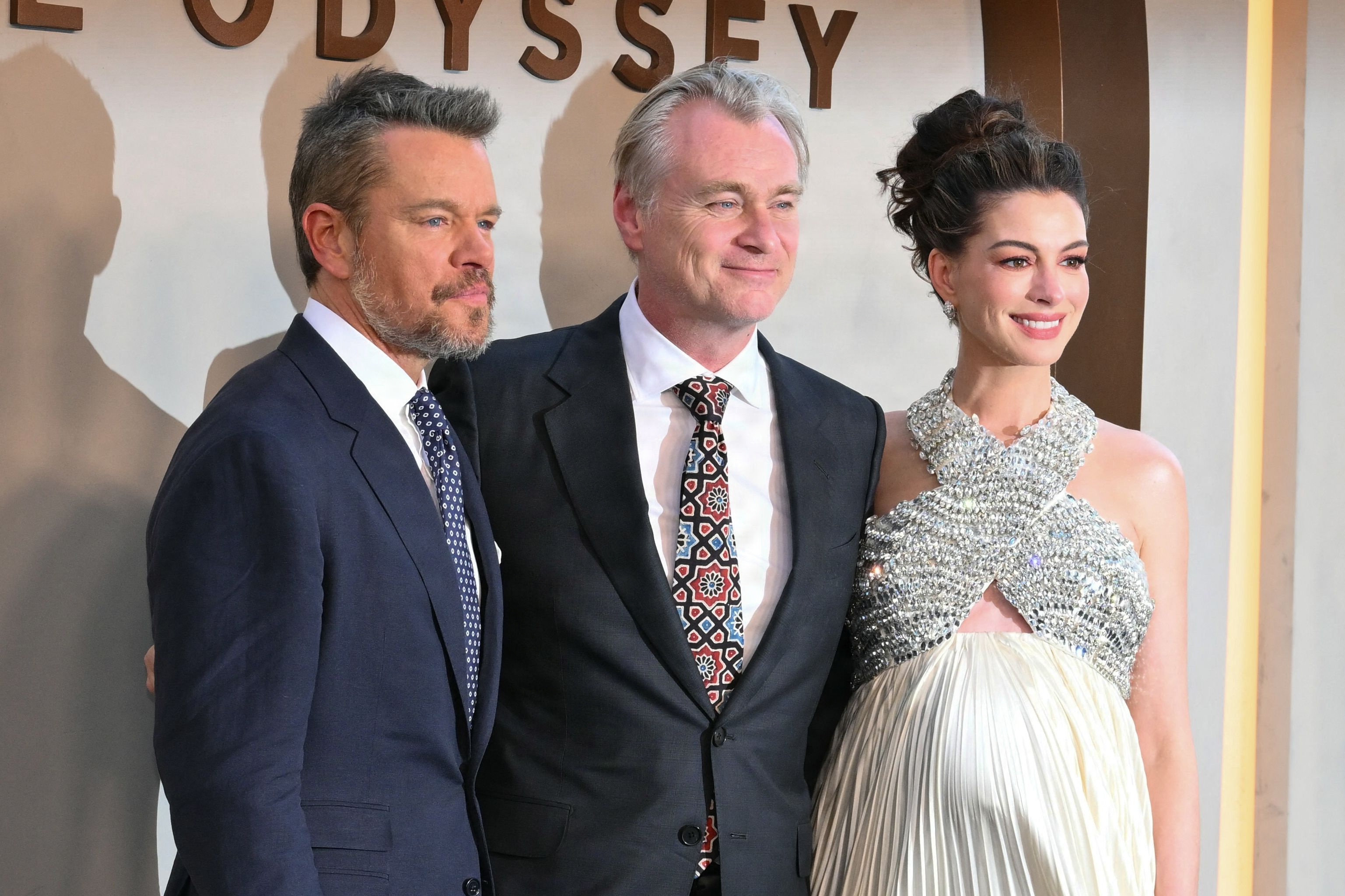 Den britisk-amerikanske instruktør Christopher Nolan er flankeret af skuespillerne Matt Damon og Anne Hathaway, der spiller hovedrollerne i Nolans nye film "The Odyssey", ved premieren i New York den 14. juli. (Arkivfoto).