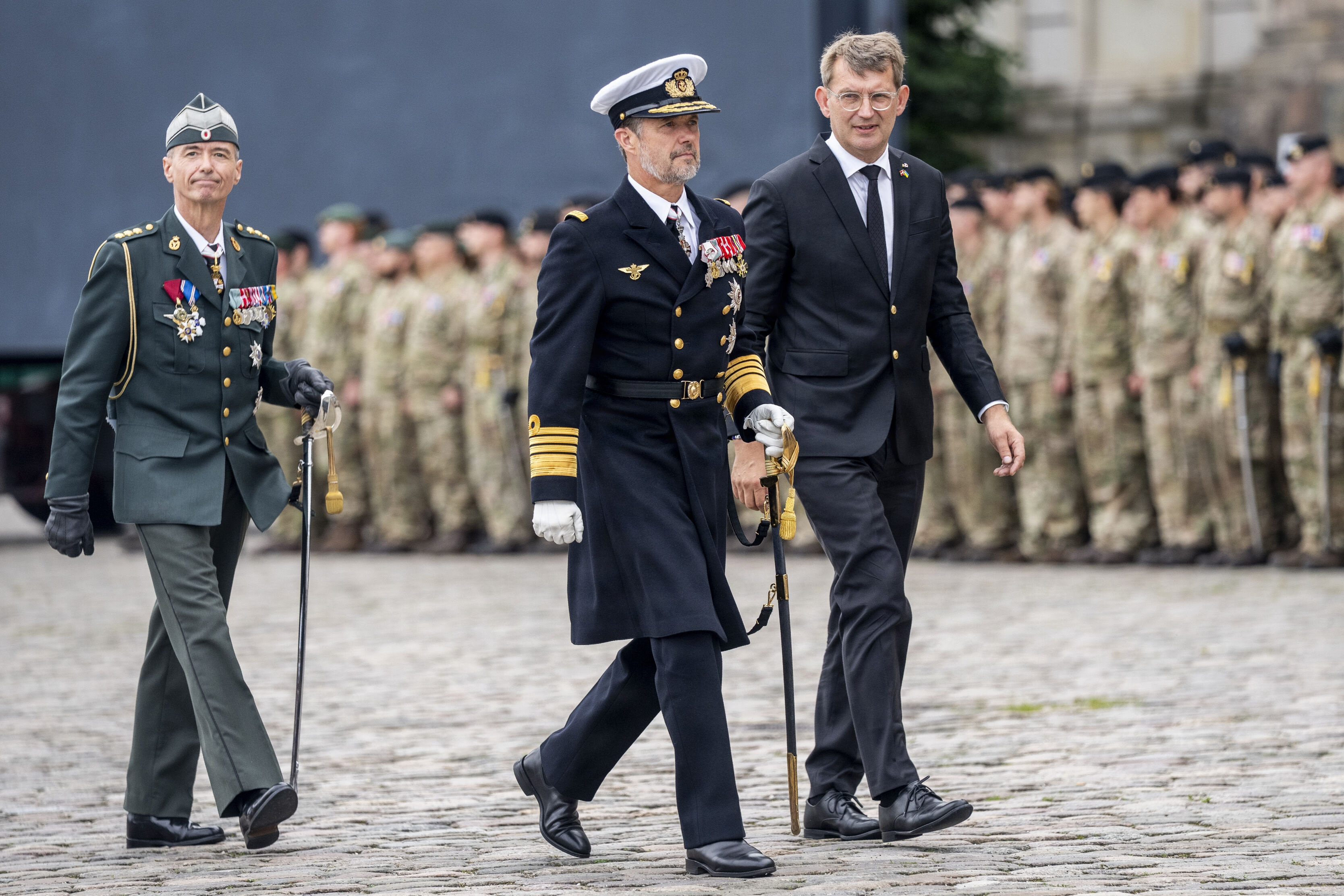 Kong Frederik deltager i flagdagen for Danmarks udsendte 5. september 2025 på Christiansborg Slotsplads flankeret af daværende forsvarsminister Troels Lund Poulsen (V) til højre og adjudantstabschef Jens Ole Rossen-Jørgensen til venstre. Sidstnævnte bliver til september udskiftet på posten. (Arkivfoto).