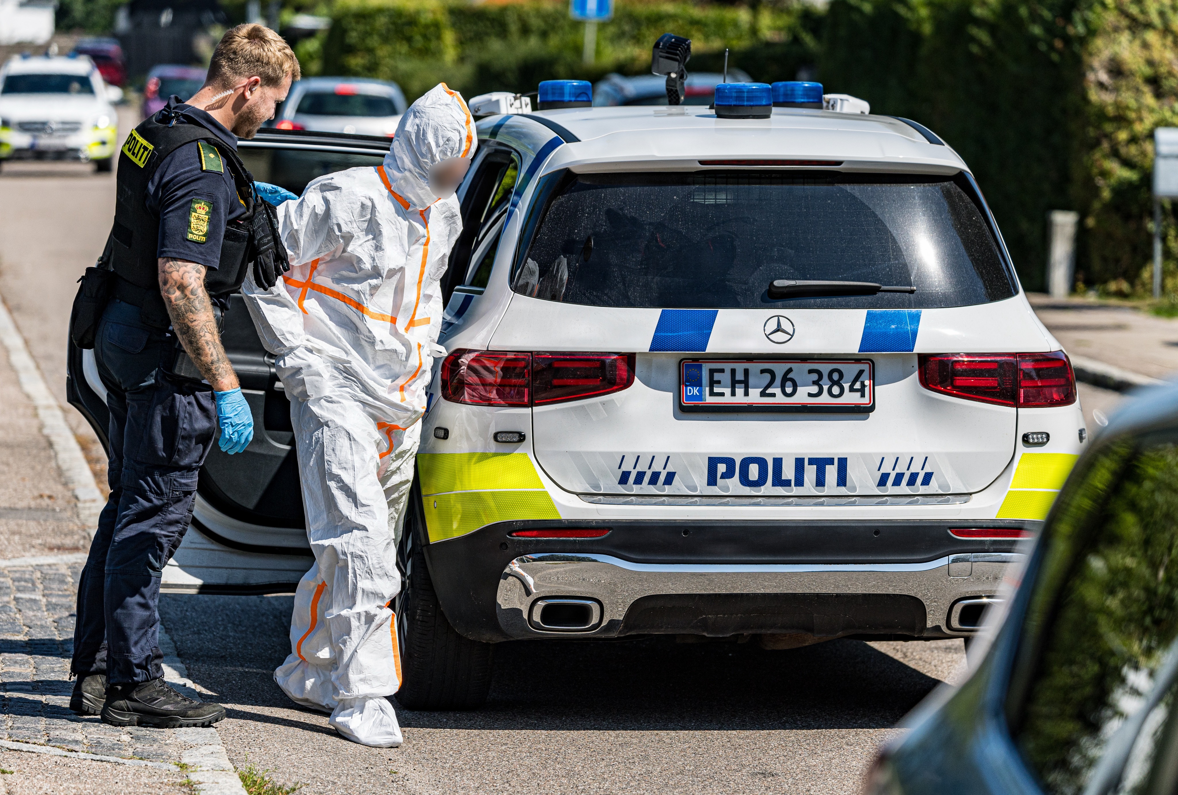 En person i DNA-dragt på Ludvig Hegners Alle føres væk. Politiet til stede på Taastrup Hovedgade torsdag den 30. juli 2026. Politiet har afgivet skud mod føreren af en efterlyst varebil, der har forsøgt at påkøre to politifolk på Taastrup Hovedgade.
