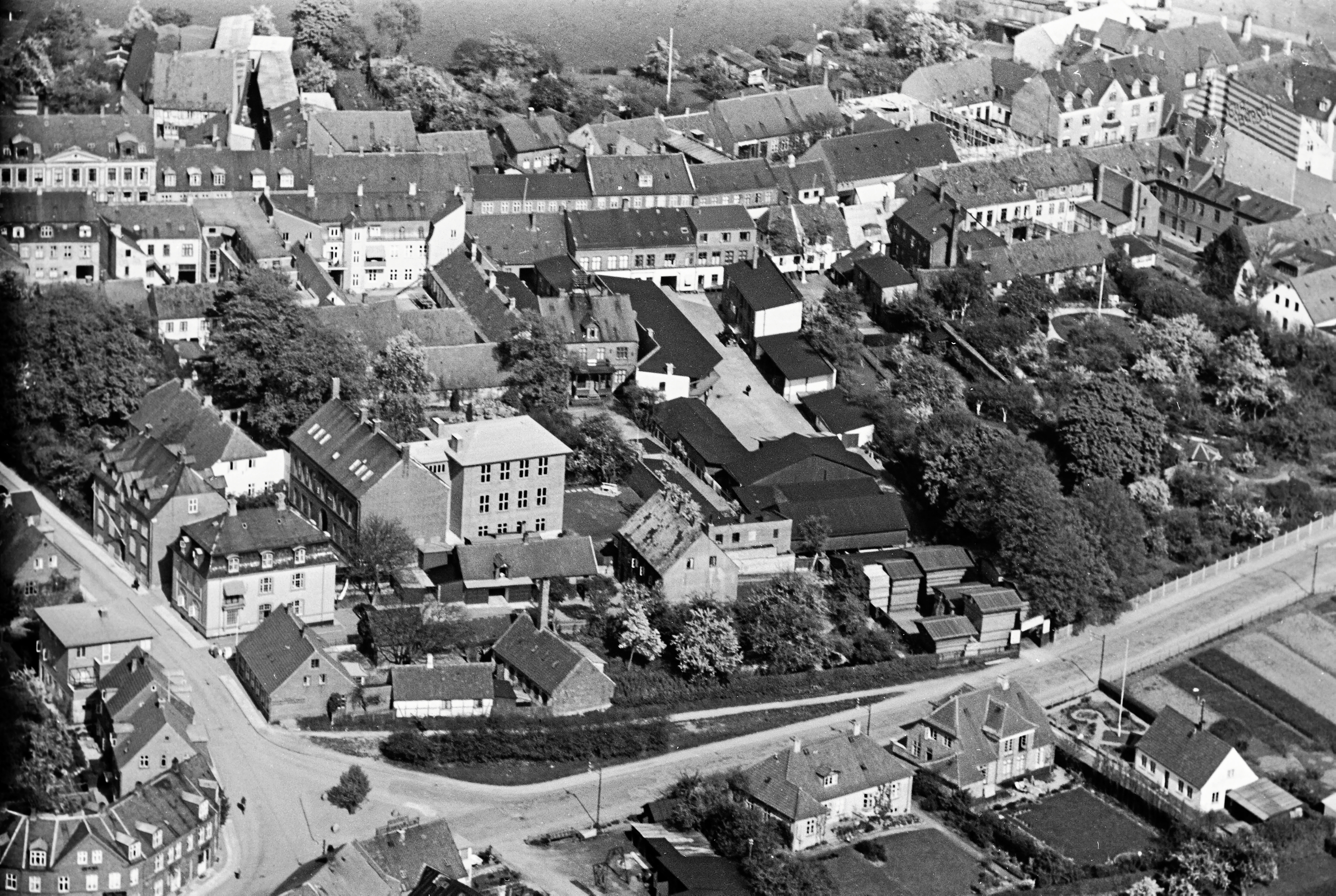 Luftfoto fra 1936 som viser Nordstensvej og Møllestræde. Midt i billedet kan man et større gårdrum bag Slotsgade 25. Her havde Hillerød Trælastforretning i mange år en lagerplads. - Tilhører Det Kgl. Bibliotek. Luftfoto fra 1936 som viser Nordstensvej og Møllestræde. Midt i billedet kan man et større gårdrum bag Slotsgade 25. Her havde Hillerød Trælastforretning i mange år en lagerplads.